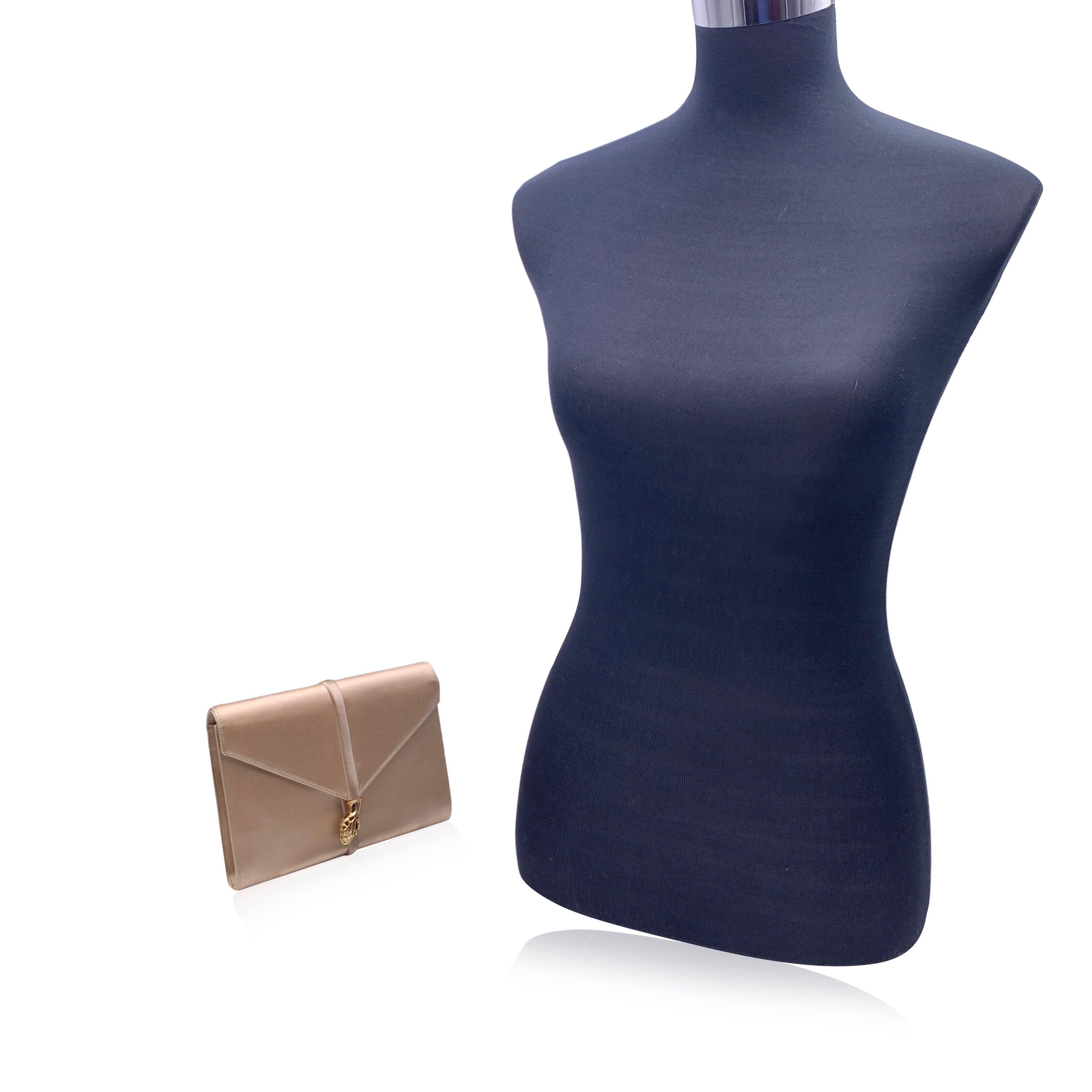 Yves Saint Laurent Vintage Clutch Bag aus beigefarbenem Satin mit goldenen Metalldetails in Form von Schlangenköpfen auf der Vorderseite. Sie hat eine Klappe mit Magnetknopfverschluss auf der Vorderseite. Futter aus Stoff. 1 offene Seitentasche