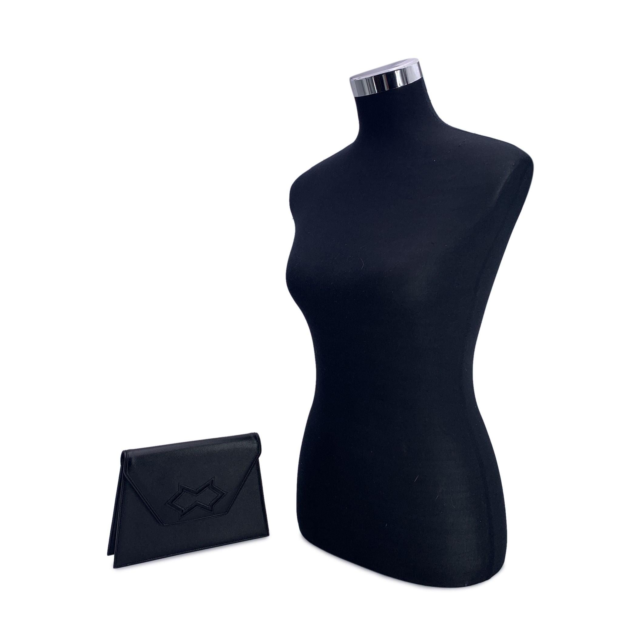 Yves Saint Laurent vintage clutch bag, crafted in black leather. Trapeze-shaped. It features a flap with magnetic button closure on the front. Beige fabric lining with YSL logos. 1 side zip pocket inside. 'YVES SAINT LAURENT' embossed inside