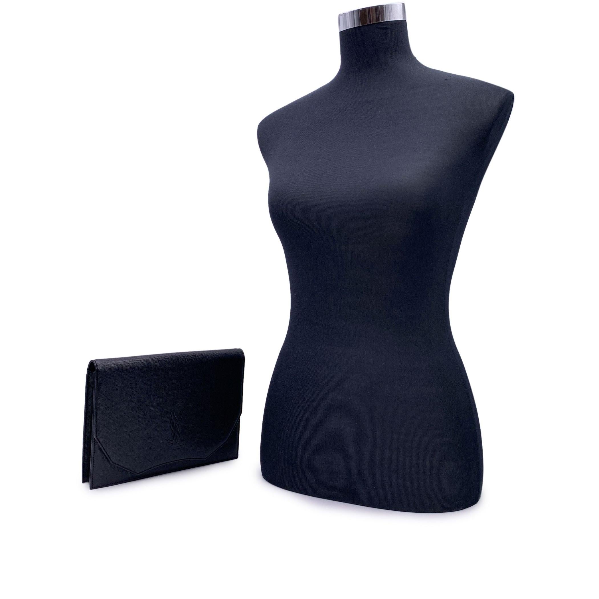 Yves Saint Laurent Vintage Clutch Bag aus schwarzem Leder. Sie hat eine Klappe mit Magnetknopfverschluss auf der Vorderseite. YSL-Logo auf der Vorderseite. 1 offene Tasche hinten. Beigefarbenes Stofffutter. 1 Seitentasche mit Reißverschluss innen.