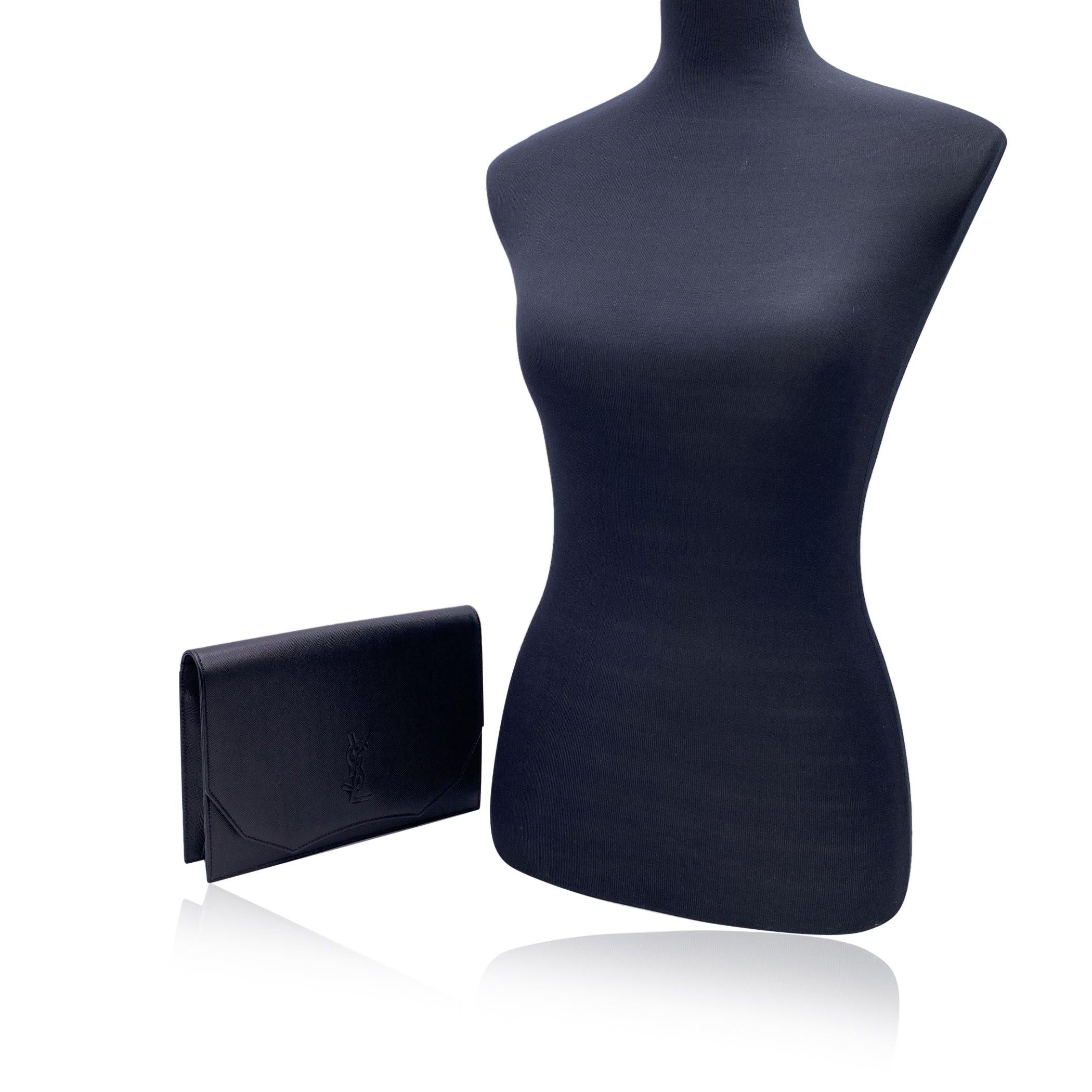 Yves Saint Laurent Vintage Clutch Bag aus schwarzem Leder. Sie hat eine Klappe mit Magnetknopfverschluss auf der Vorderseite. YSL-Logo auf der Vorderseite. 1 offene Tasche hinten. Beigefarbenes Stofffutter. 1 Seitentasche mit Reißverschluss innen.