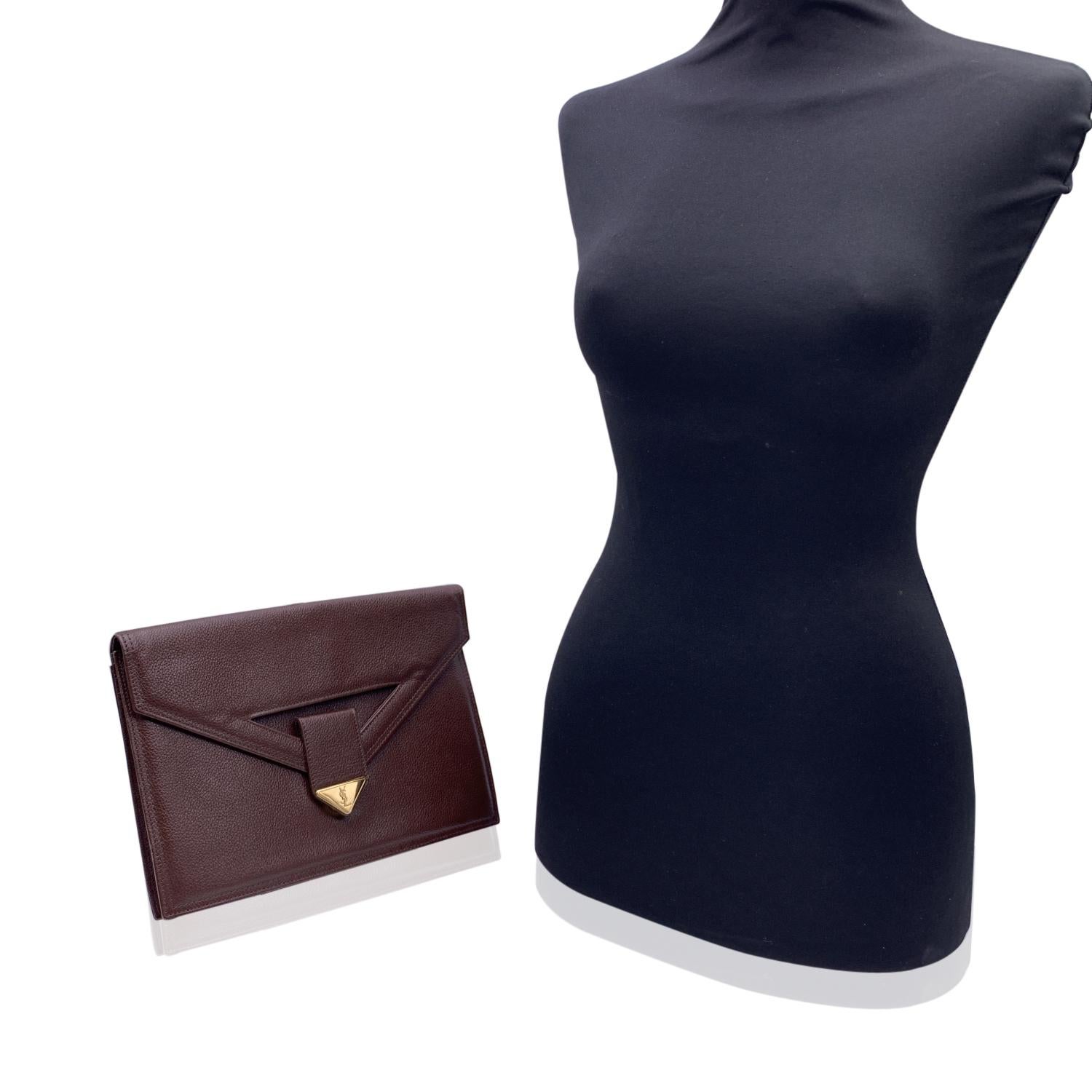 Yves Saint Laurent vintage clutch bag, crafted in brown eather. It features a flap with magnetic button closure on the front. Gold metal YSL logo tab on the front. 1 rear open pocket. Brown fabric lining. 1 side zip pocket inside. 'YVES SAINT