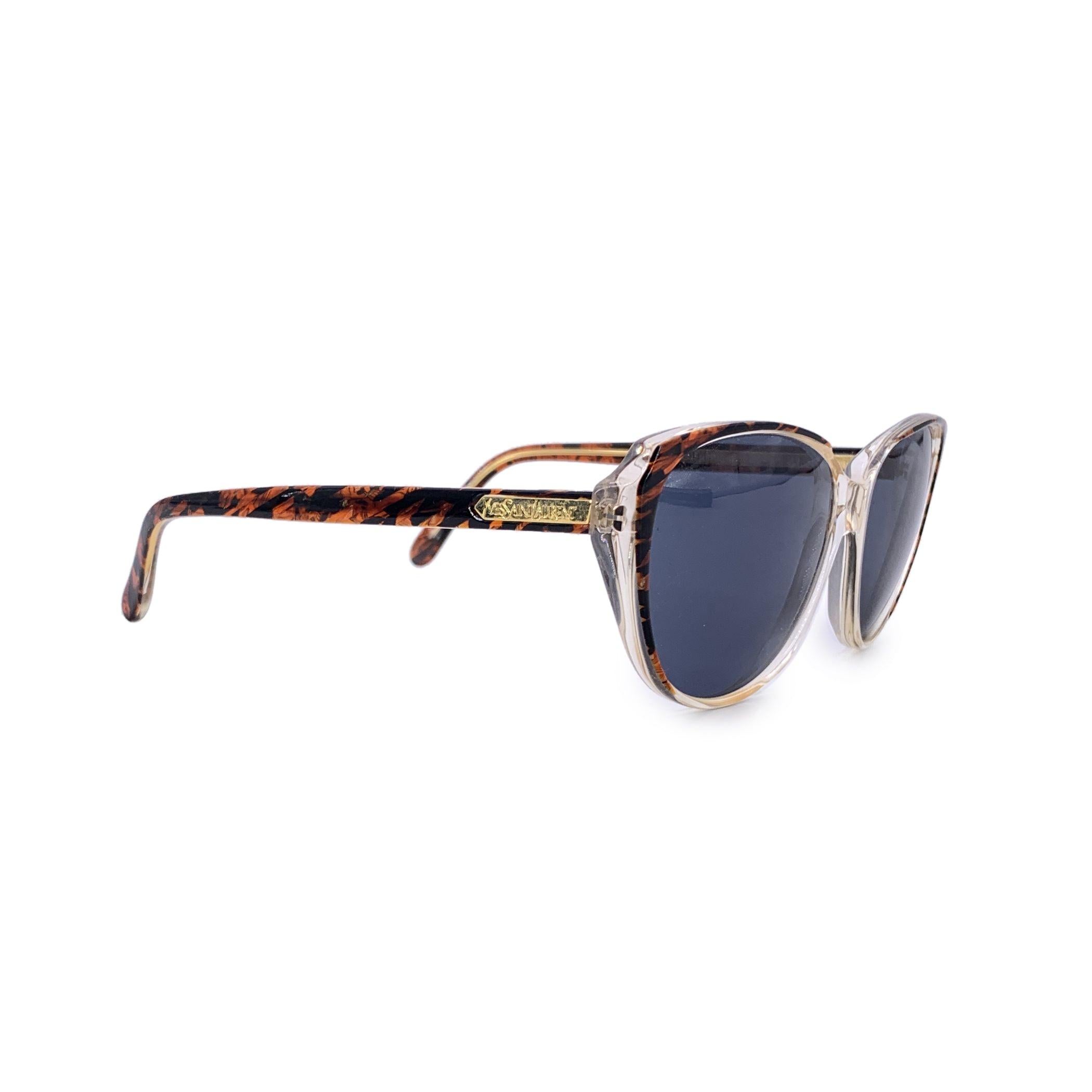 Genießen Sie die raffinierte Eleganz der 1980er Jahre mit dieser Vintage-Sonnenbrille von Yves Saint Laurent, Modell Menphis (56/14) - ein seltenes und wunderschön erhaltenes Stück, das den raffinierten Glamour der Ära einfängt. Dieses in Frankreich
