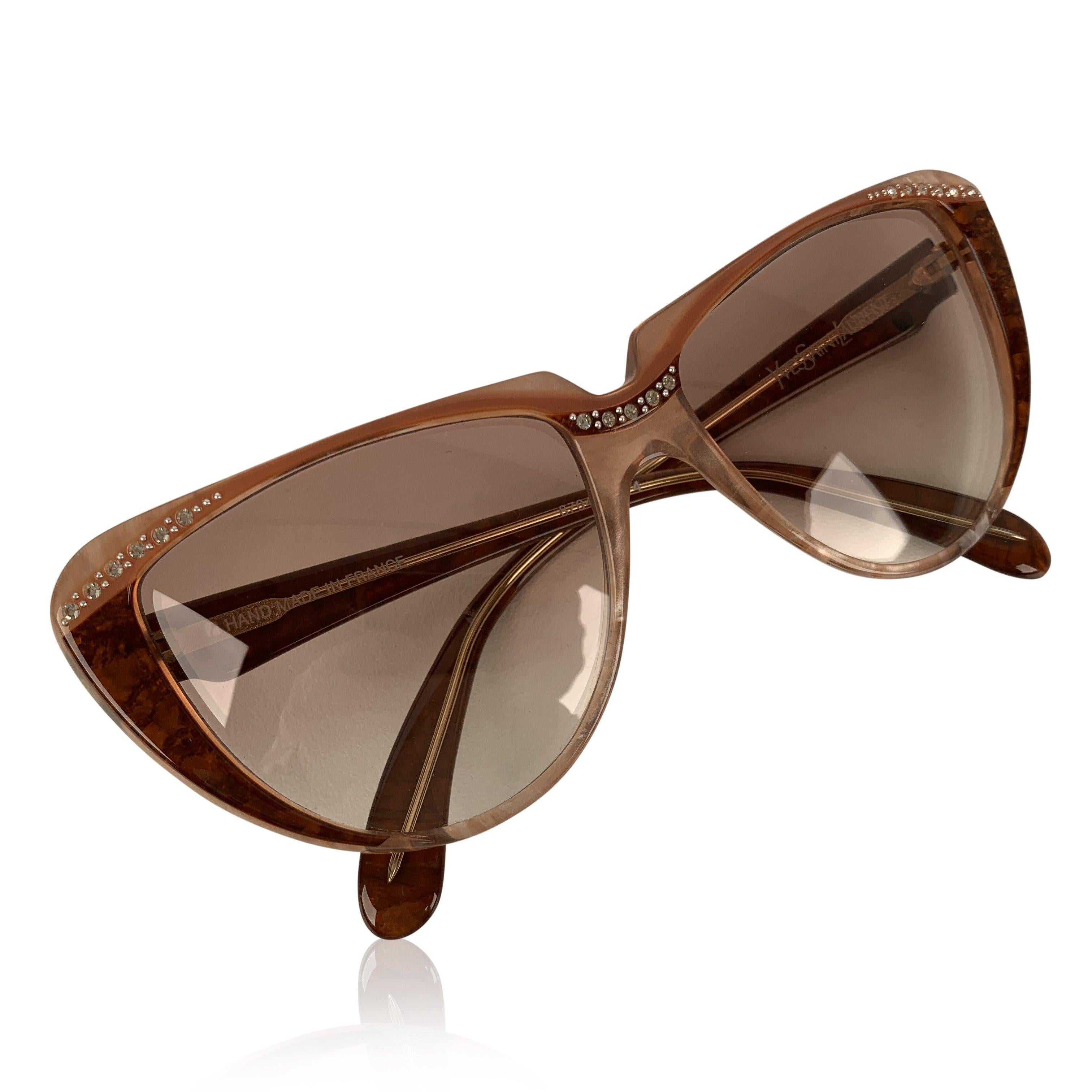 Cat-eye vintage sunglasses by YVES SAINT LAURENT from the 80s, Mod. 8704 PO 74. Pink and brown frame embellished with small rhinestones on the nose bridge amd on corners. Hand-Made in France. YSL logos on the side. New 100% UV protection gradient