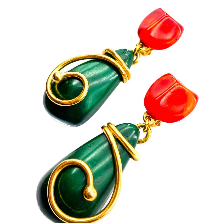 The earrings are from the House of YVES SAINT LAURENT. These are hanging clips, orange-red at the clasp, green covered with gold metal on the pendant side.
The clips are in very good condition despite a trace on the top of the pendant of one of