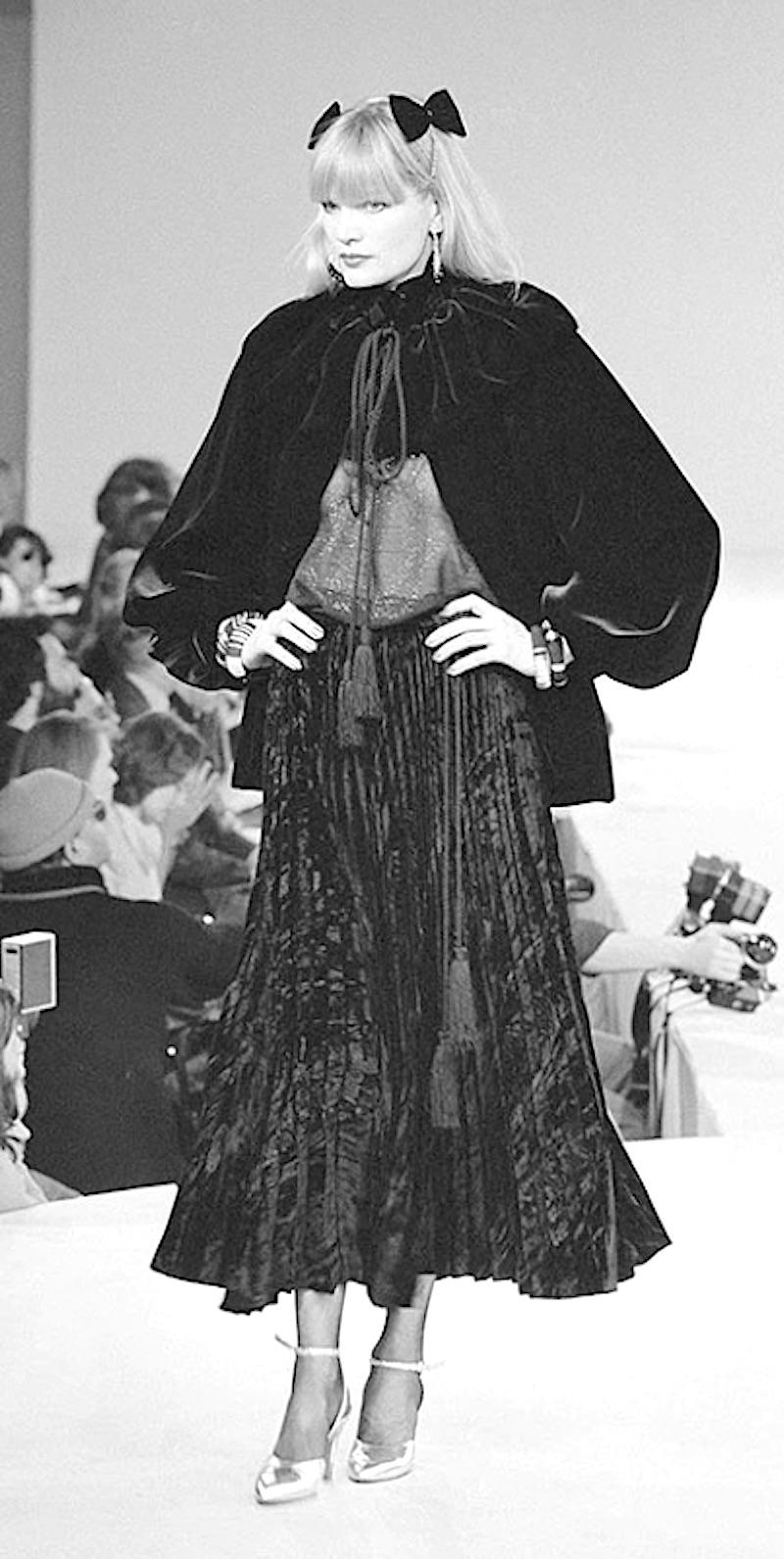 Beautiful fall 1980 black velvet Yves Saint Laurent jacket with side pockets, balloon sleeves and a long rope with tassel ends for closure at neck. Capelet ruffle on shoulders. 
Condition: Excellent, fits best on a size small French 36/38
