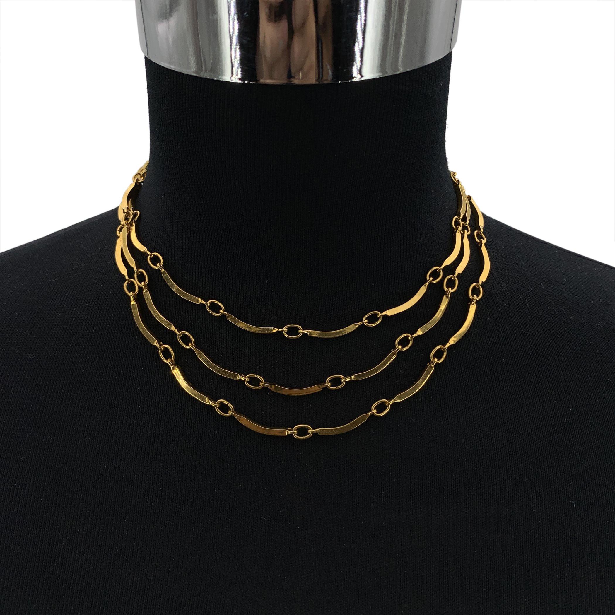 Verleihen Sie Ihrer Schmucksammlung einen Hauch von Vintage-Eleganz mit dieser dreireihigen Halskette von Yves Saint Laurent, einem raffinierten Stück aus der goldenen Ära des YSL-Designs. Die aus goldfarbenem Metall gefertigten, gestuften Stränge