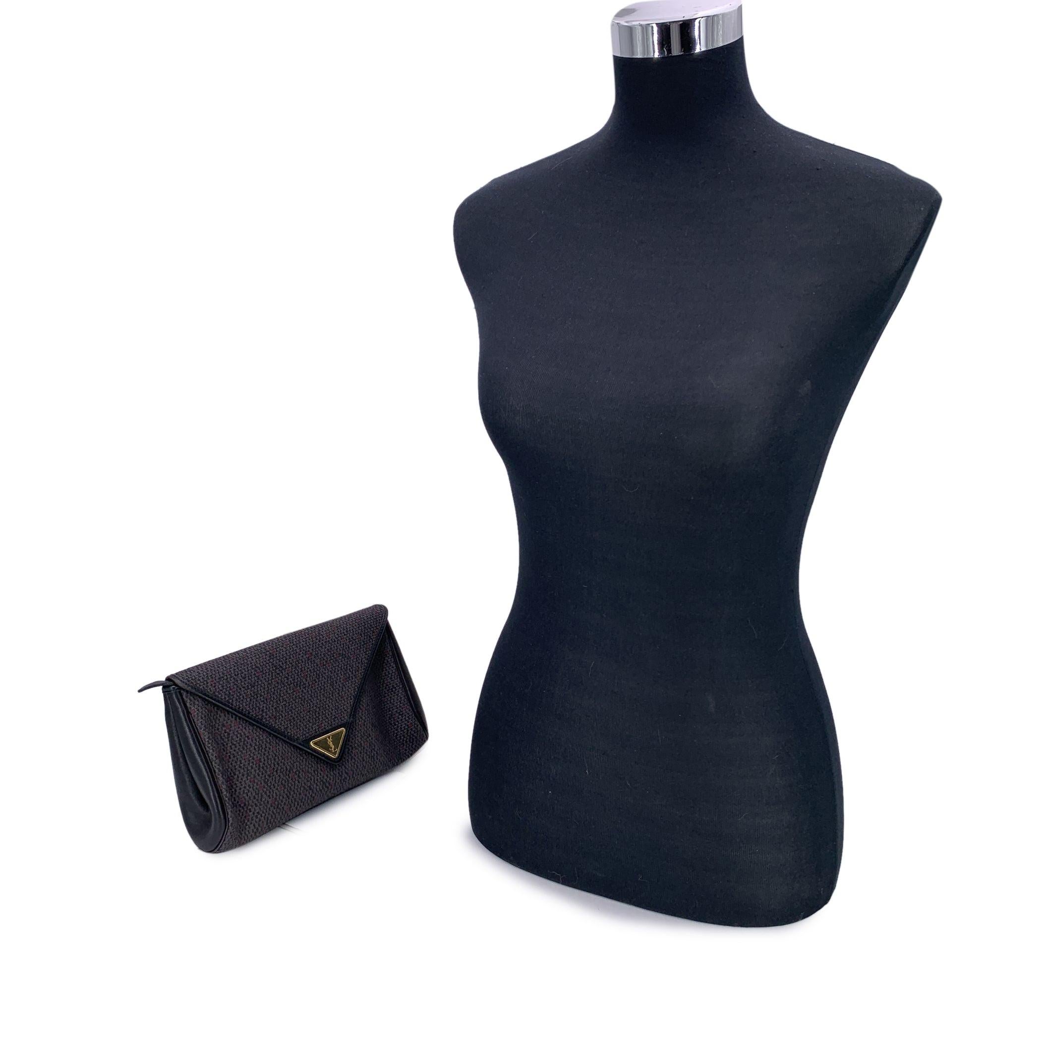 Chic and timeless, this vintage Yves Saint Laurent clutch is a refined statement of understated luxury. Crafted from grey textured vinyl canvas with black leather trim, it effortlessly balances classic elegance with a striking pop of color. The