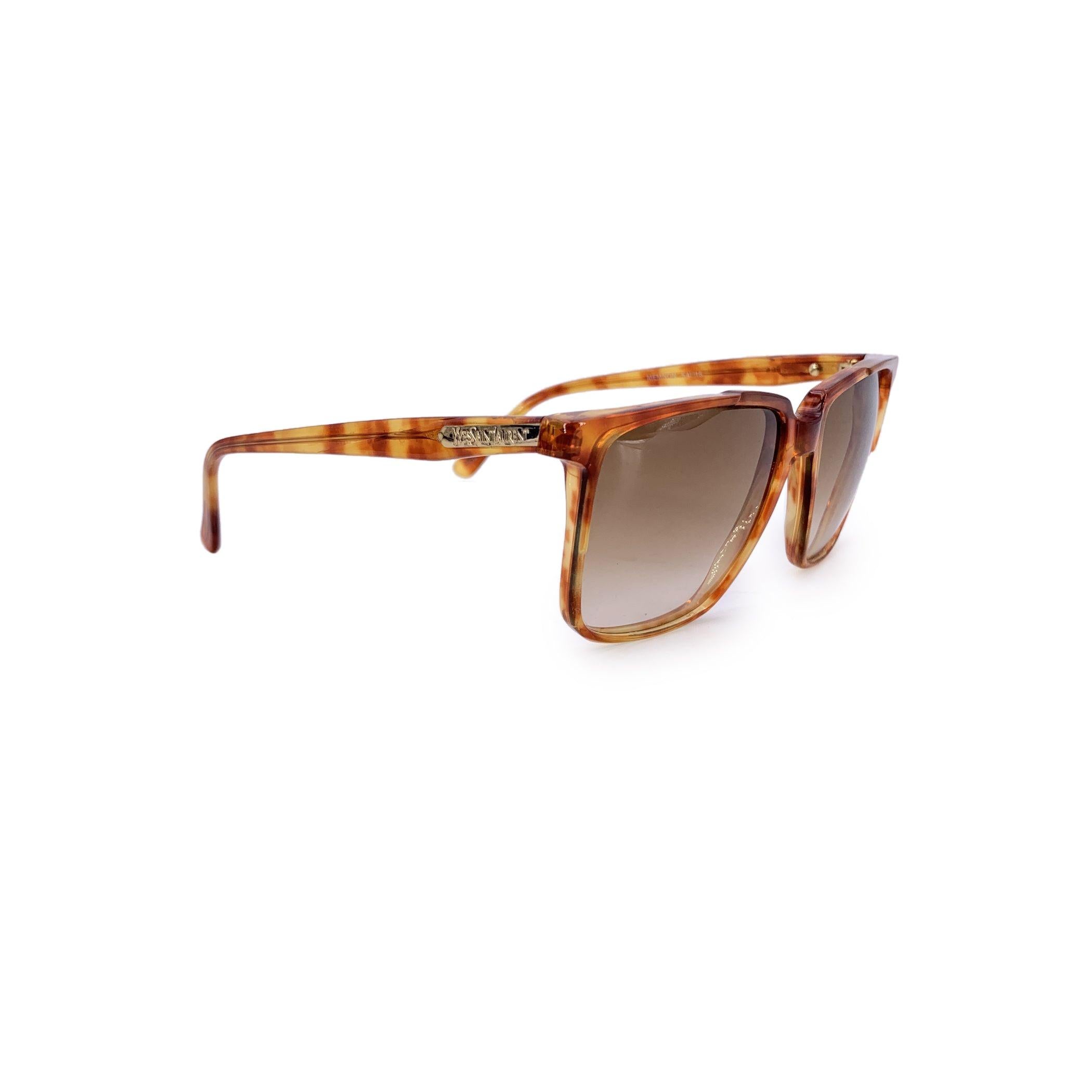 Zeitlose Raffinesse mit dieser Yves Saint Laurent-Sonnenbrille im Vintage-Stil, Modell Memnon - ein markantes Unisex-Design, das Retro-Charme mit Alltagstauglichkeit verbindet. Der rechteckige Rahmen aus hellbraunem Havanna-Acetat hat einen warmen,
