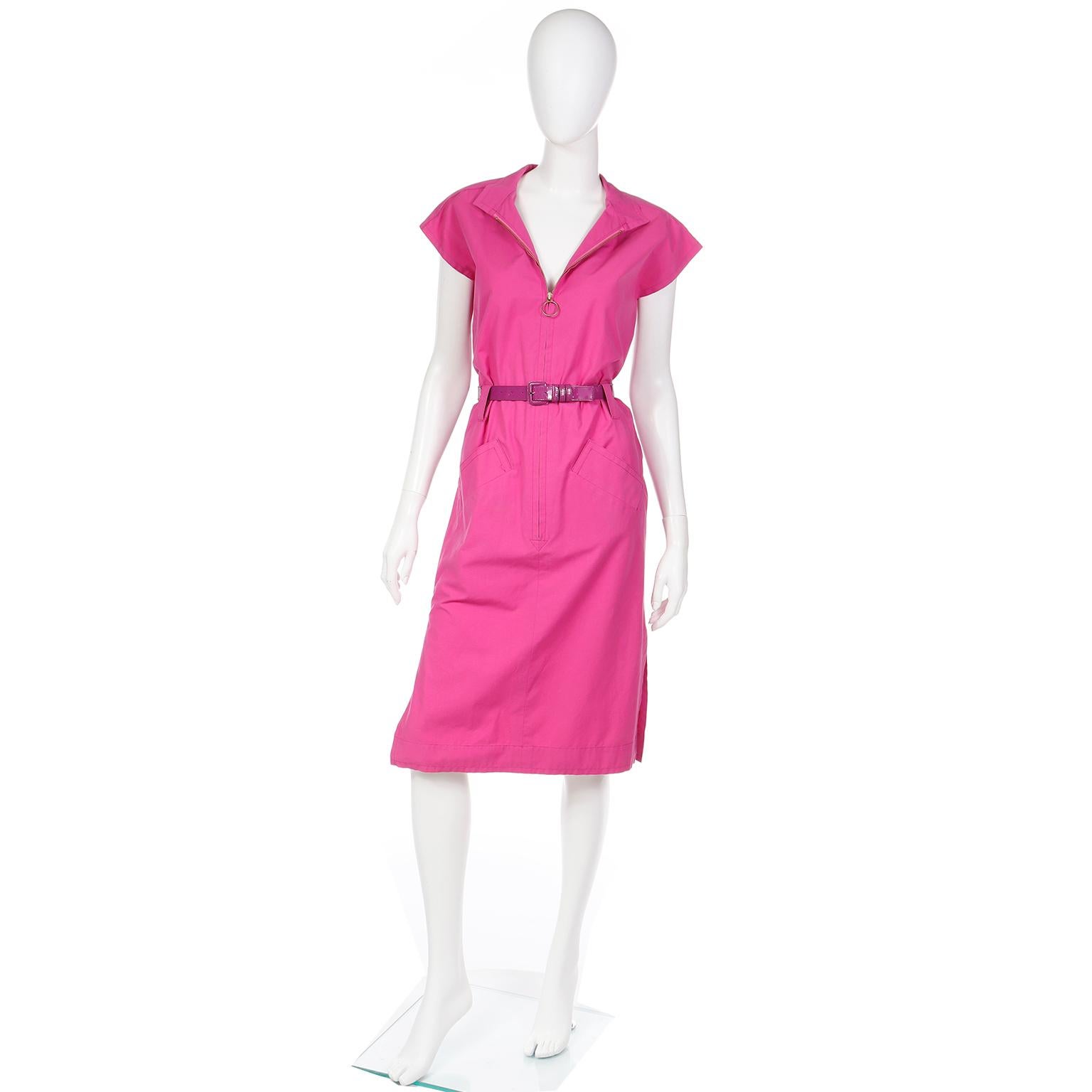 This lovely vintage early 1980s Yves Saint Laurent dress is in a pretty pink cotton. The dress has 2 front patch pockets, a mandarin collar, cap sleeves, and slits in the skirt with a front zip closure with a loop pull. This dress comes with both a