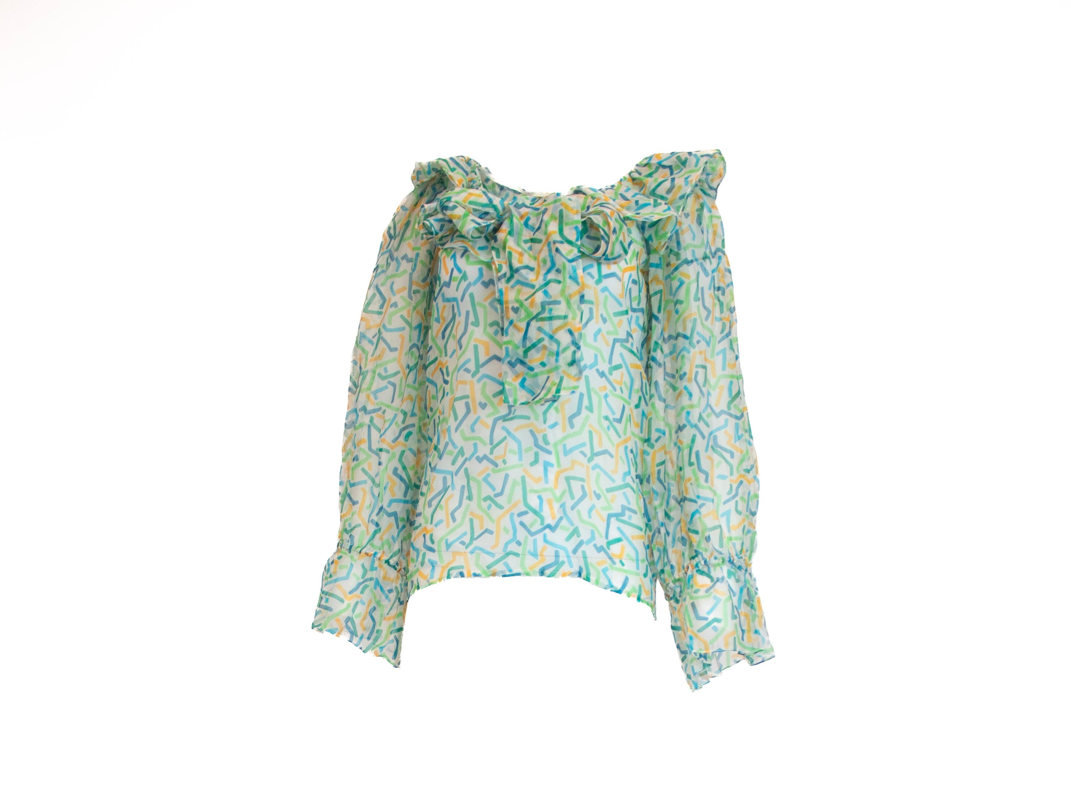 Esta blusa vintage Yves Saint Laurent de la primavera/verano de 1983 presenta un lujoso tejido de seda adornado con un estampado abstracto, que ofrece una estética atemporal pero juguetona. Su cuello con volantes y sus mangas abullonadas añaden un