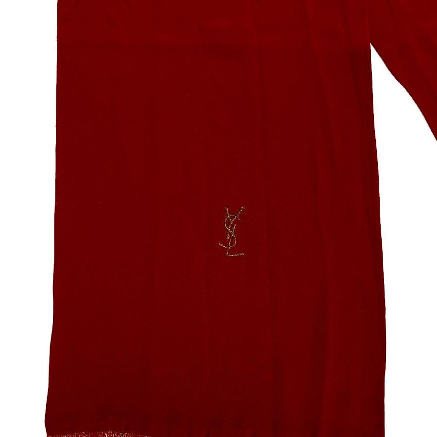 Beautiful  Yves Saint Laurent scarf in red silk, bordered with fine red and gold fringes. The initials of the brand are embroidered in gold thread on the bottom of the scarf.
The scarf is in very good condition, it has a small stain (see photo), and