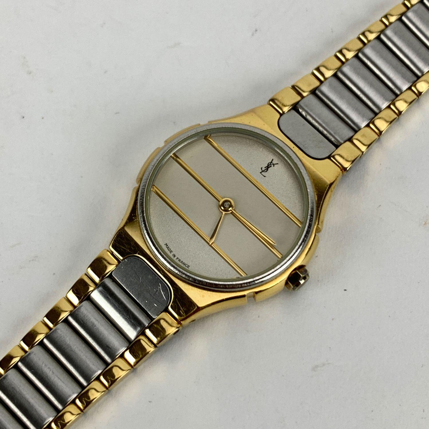Vintage Yves Saint Laurent wrist watch. Model 219091 . Gold-tone and silver-tone stainless steel round case (23 mm). White dial with gold metal stripes. Stainless steel strap. Circumference at wrist: 6 inches - 15.2 cm

Condition

A - EXCELLENT

The
