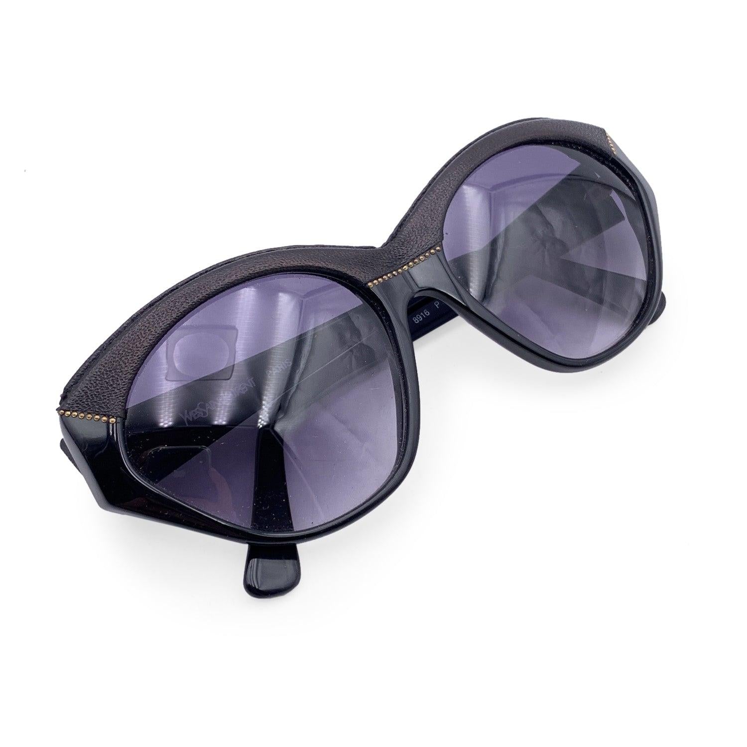 Vintage sunglasses by YVES SAINT LAURENT from the 80s, Mod. 8916 P367. Black acetate frame with gold metal accents. The upper part of the frame is covered with black leather. Hand-Made in France. Logos on the side. New 100% UV protection gradient