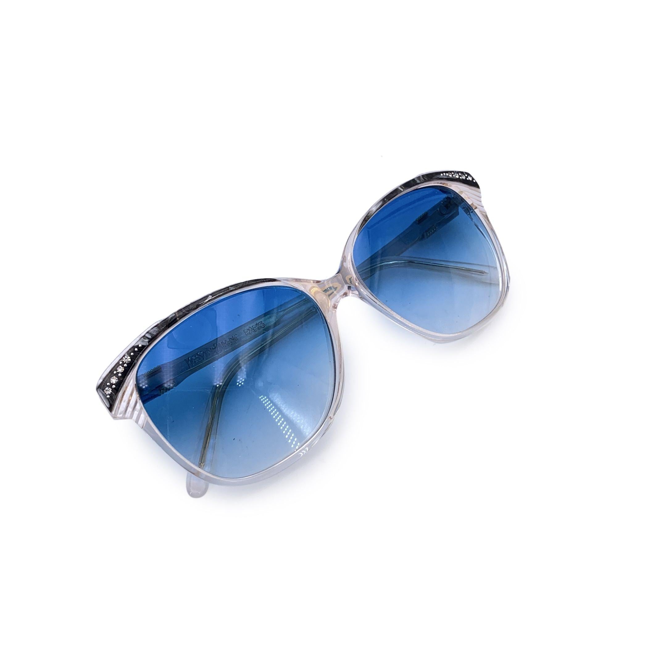 Una visione di contrasto e couture, questi occhiali da sole Yves Saint Laurent Vintage White con lenti blu sono un cenno abbagliante alla giocosa raffinatezza della moda degli anni Ottanta. Progettato e realizzato in Francia, questo modello cat-eye