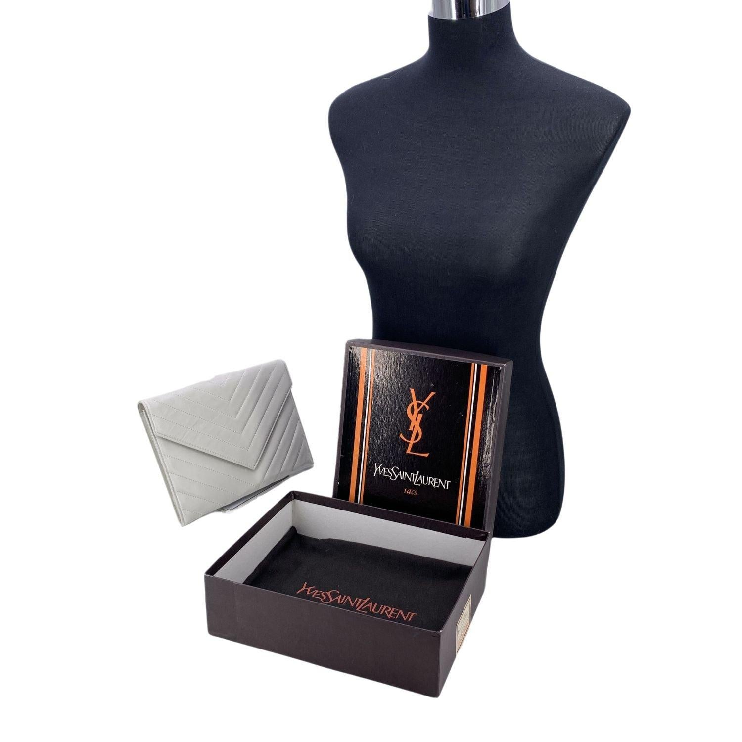 Pièce intemporelle de l'âge d'or du glamour parisien, cette pochette Yves Saint Laurent en élégant cuir blanc matelassé en V est une véritable ode à la sophistication. Sa silhouette structurée s'ouvre par un rabat classique et une fermeture à bouton