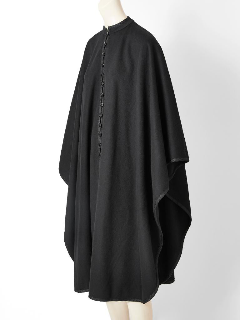 Yves Saint Laurent, black wool, cape having a Mandarin collar, passementerie trim, and front button closure detail. 