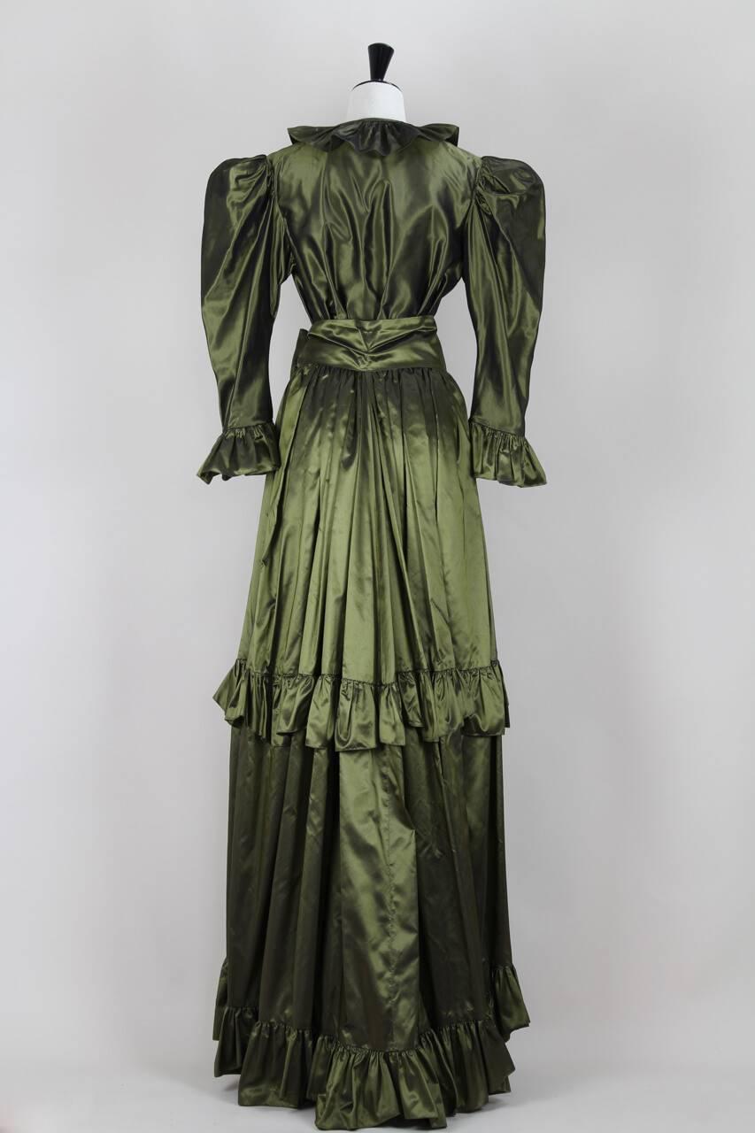 Il s'agit d'une exceptionnelle robe deux pièces en taffetas de soie vert olive irisé d'Yves Saint Laurent datant de 1978. Cette version Rive Gauche aurait été basée sur les robes Haute Couture de la collection 1977/1978. L'ensemble comprend une jupe