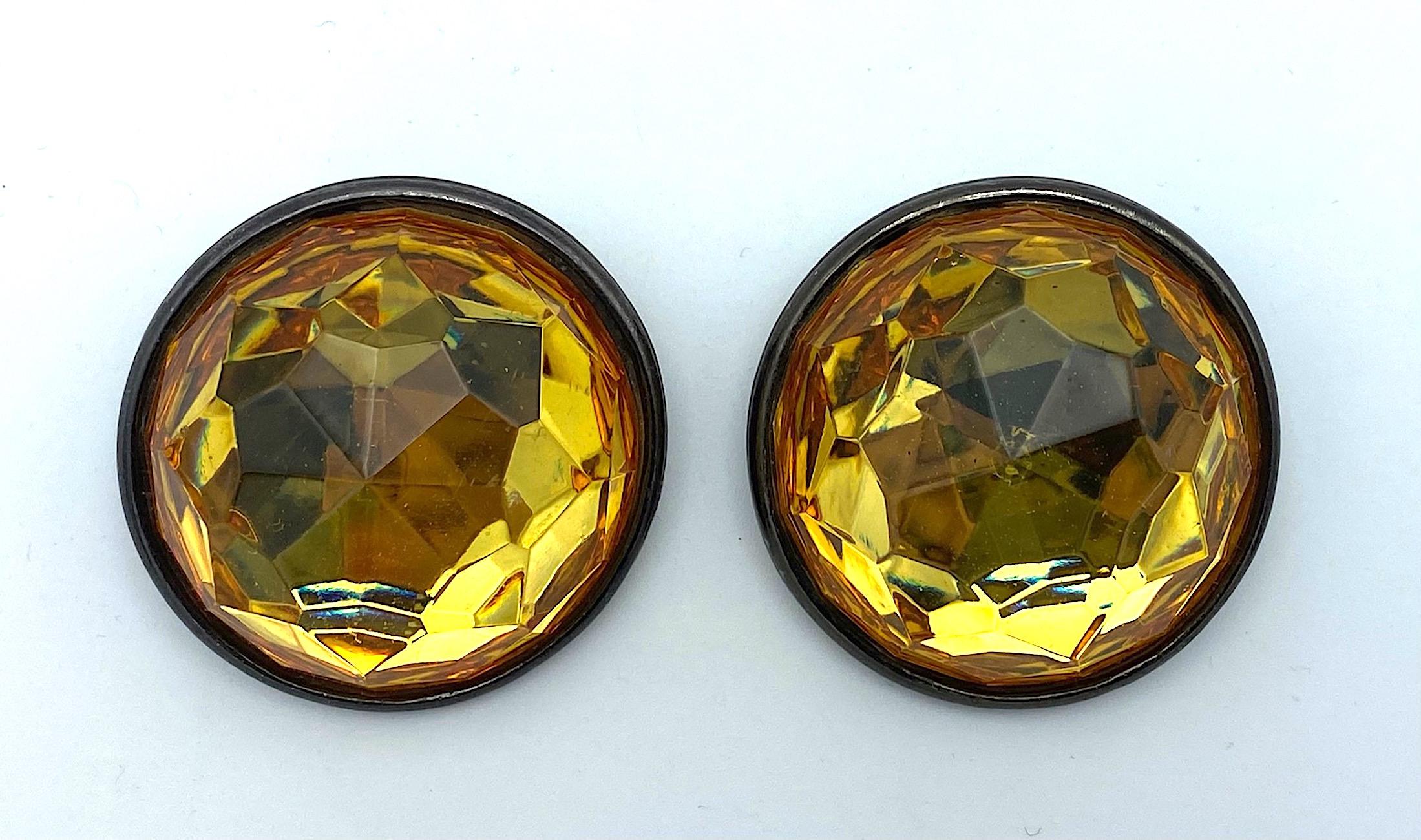 Truly a statement pair of Yves Saint Laurent earrings from the 1980s. Each earrings is 2 inches in diameter. The back are are a charcoal grey enamel on a martele textured metal disk. The fronts are large clear gold color faceted lucite dome or