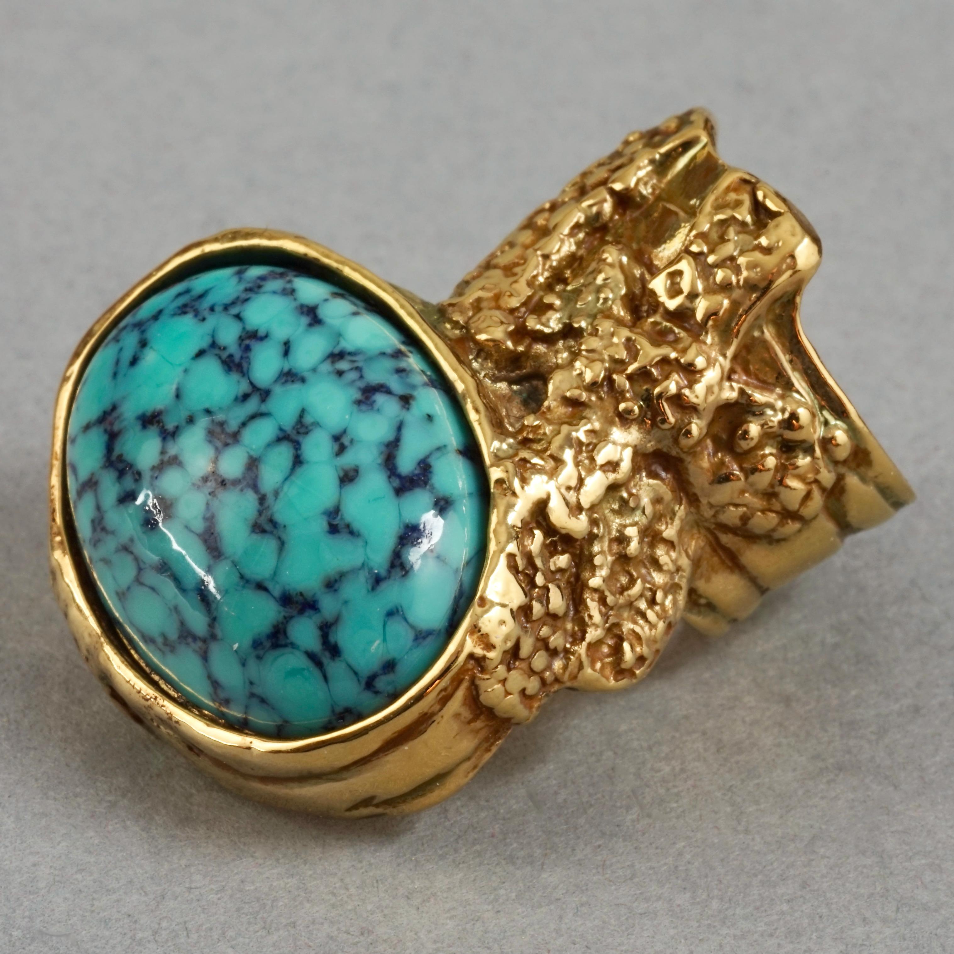 YVES SAINT LAURENT YSL Arty Turquoise Ring

Measurements:
Height: 1.49 inches (3.8 cm)
Width: 1.18 inches (3 cm)
Size: US6

Features:
- 100% Authentic YVES SAINT LAURENT.
- Textured ring with turquoise cabochon stone.
- Gold tone.
- Signed YVES