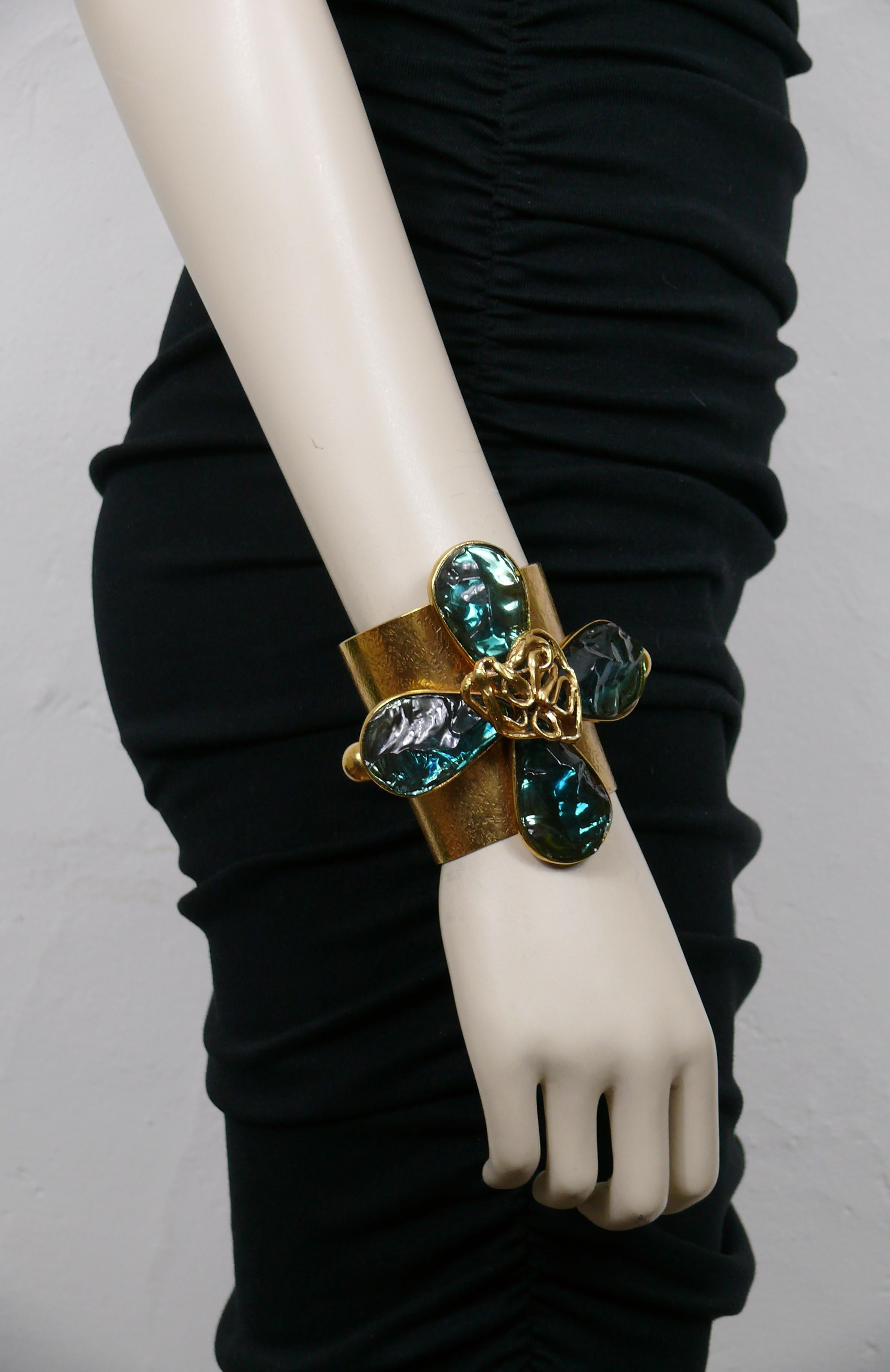 YVES SAINT LAURENT by ROBERT GOOSSENS vintage rare textured gold tone cuff bracelet featuring a massive stylized four clover centrepiece embellished with irregular shaped acqua blue resin petals and an openwork heart.

Embossed YVES SAINT LAURENT