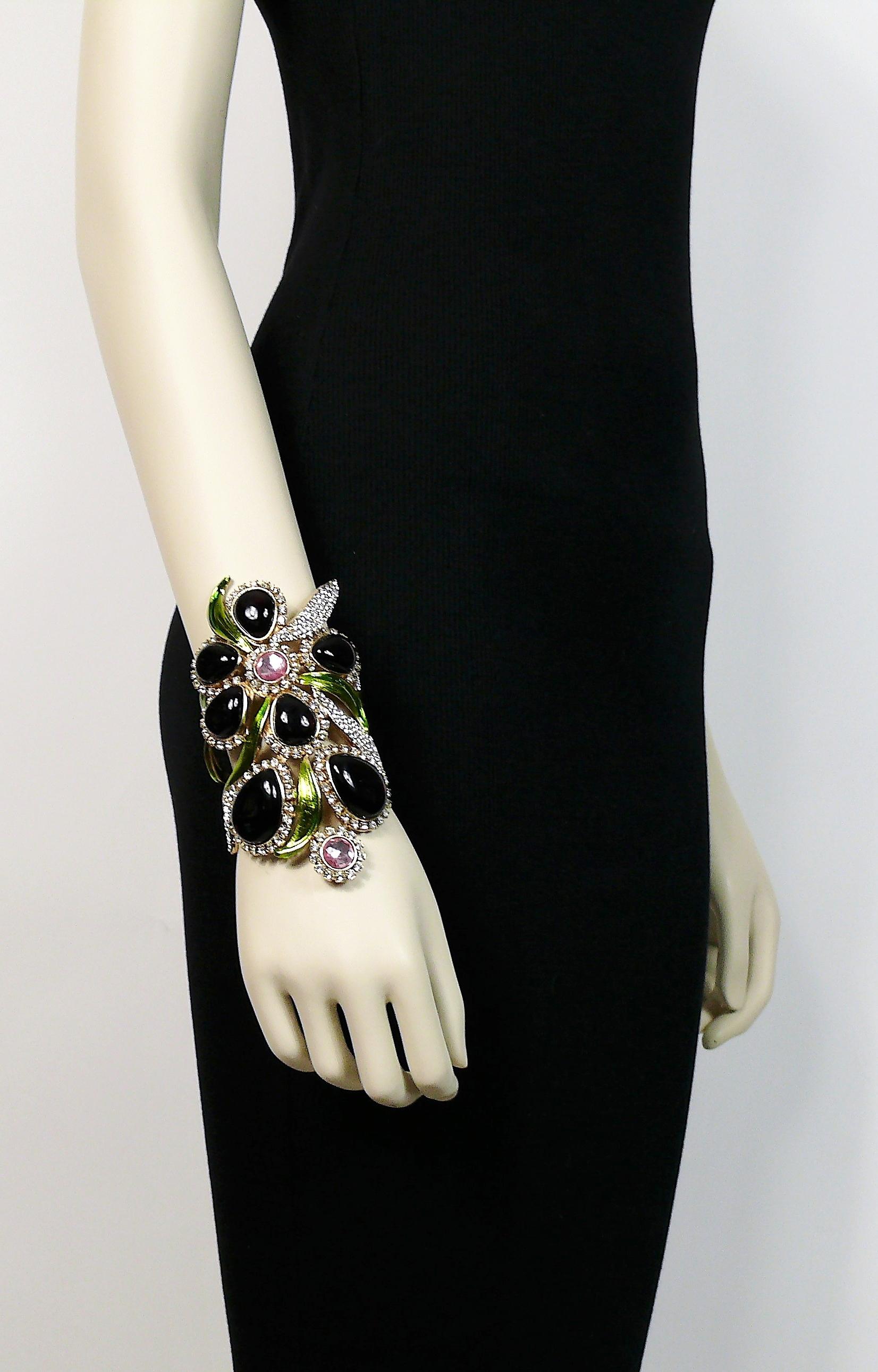 YVES SAINT LAURENT rare orchid cuff bracelet featuring deep purple glass cabochons, pink and clear crystals, green enameled leaves in a light gold toned setting.

Similar models on the Spring-Summer 2004 YVES SAINT LAURENT RTW runway show.

Embossed