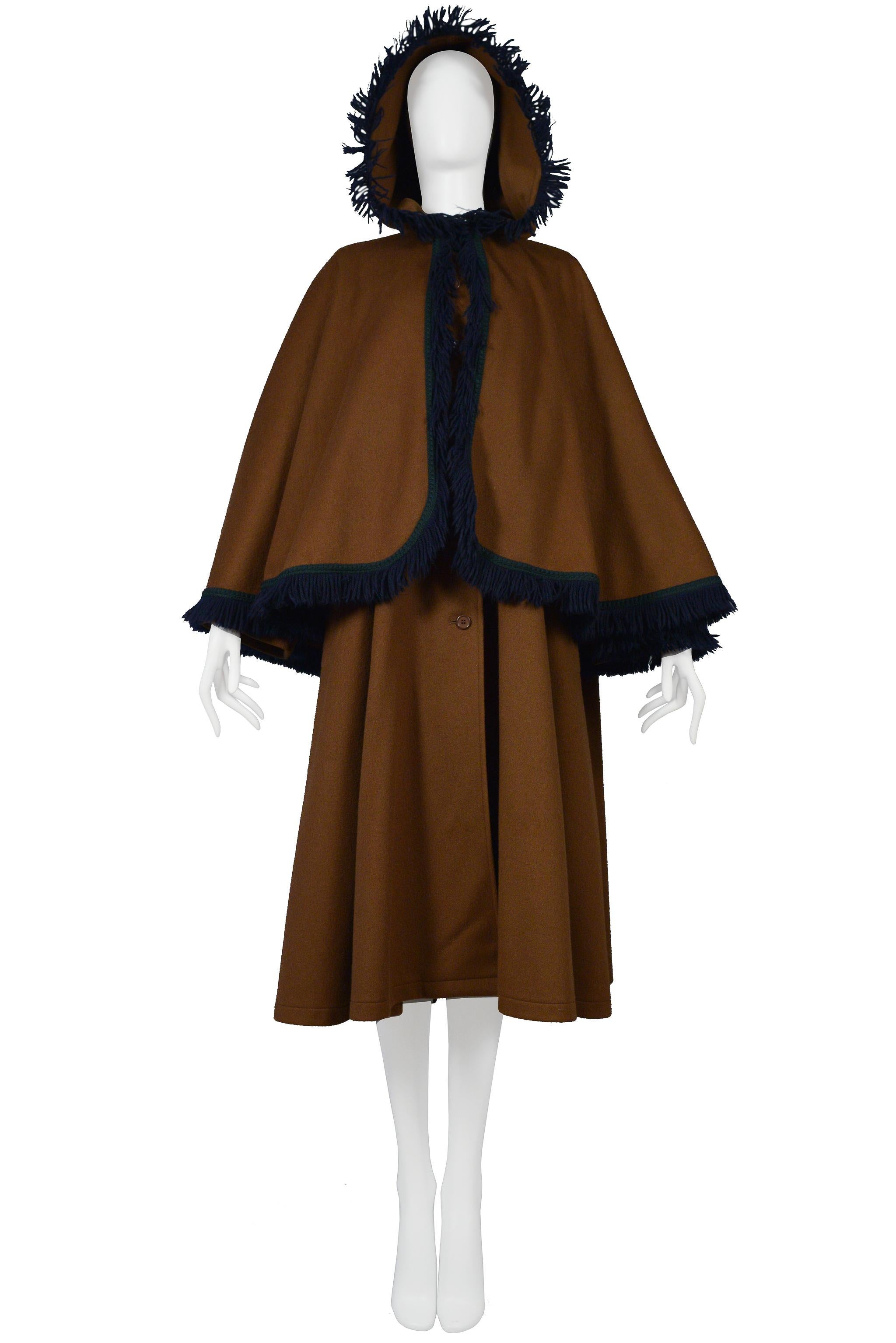 Resurrection Vintage is excited to offer a vintage Yves Saint Laurent caramel brown wool cape coat featuring an oversized hood trimmed with navy blue cotton fringe, attached capelet, hidden button front, and side pockets. 

Yves Saint Laurent
Size