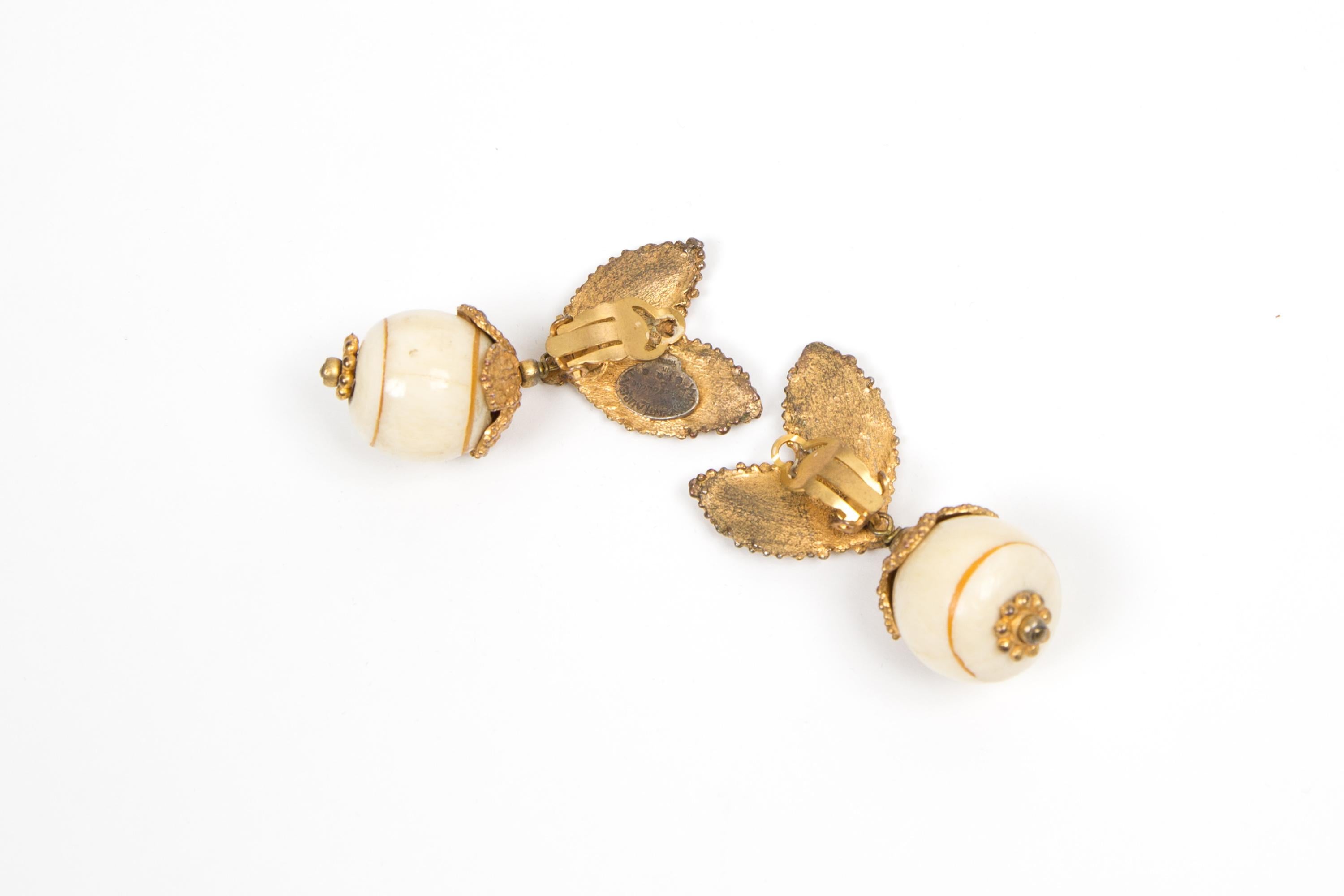 Yves Saint Laurent YSL embellished clip on earrings featuring ivory round beads with gold-tone leaves, back plaque pitted. 
Made in France, pitted logo YSL on one clip.
Circa 1980s. They come as a pair.
2.3in. (6cm) X 1.18in. (3cm) 
In good vintage