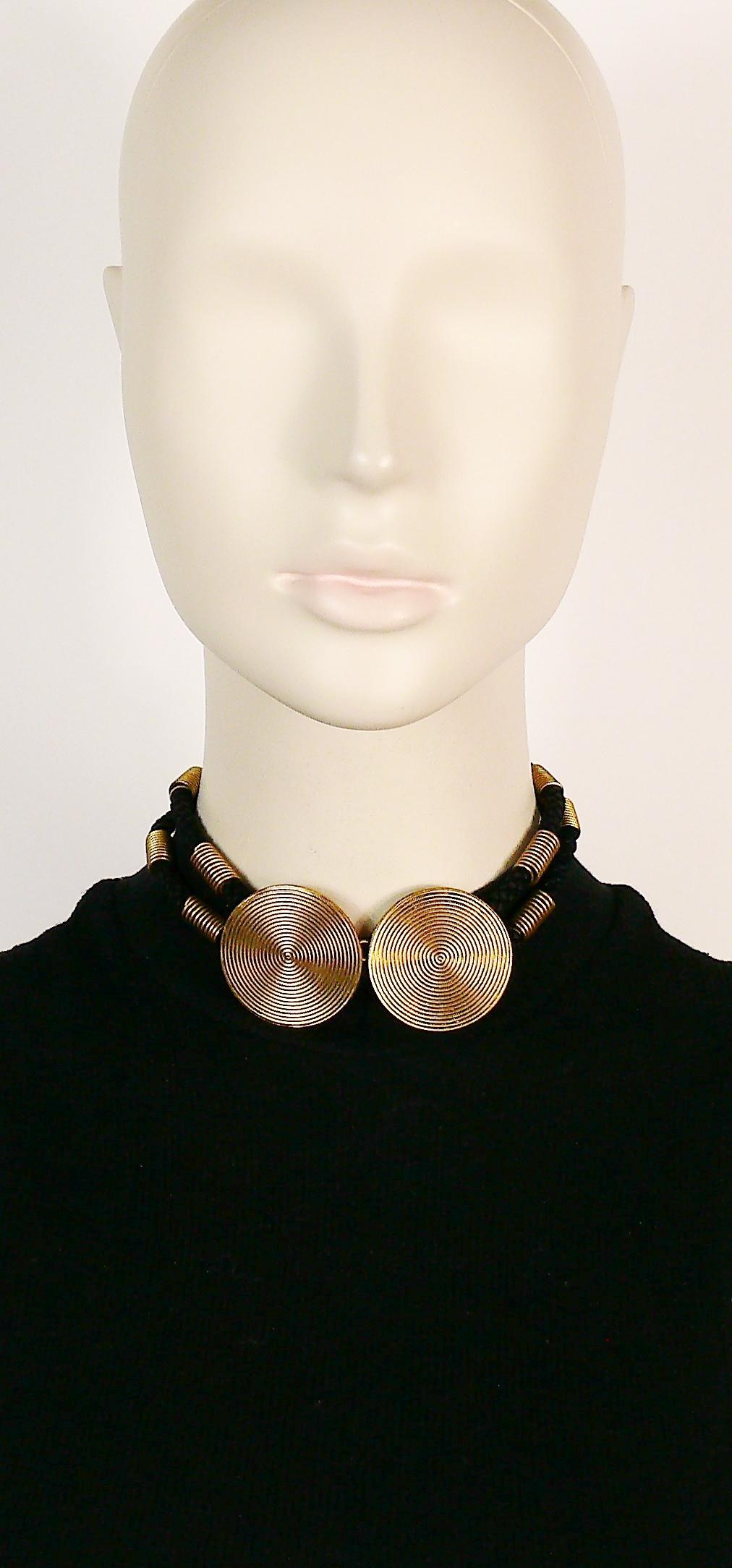 YVES SAINT LAURENT vintage choker necklace featuring two concentric antiqued gold toned discs and two black cords embellished with spring design elements.

Hook clasp closure.

Embossed YSL.

Indicative measurements : length approx. 34 cm (13.39
