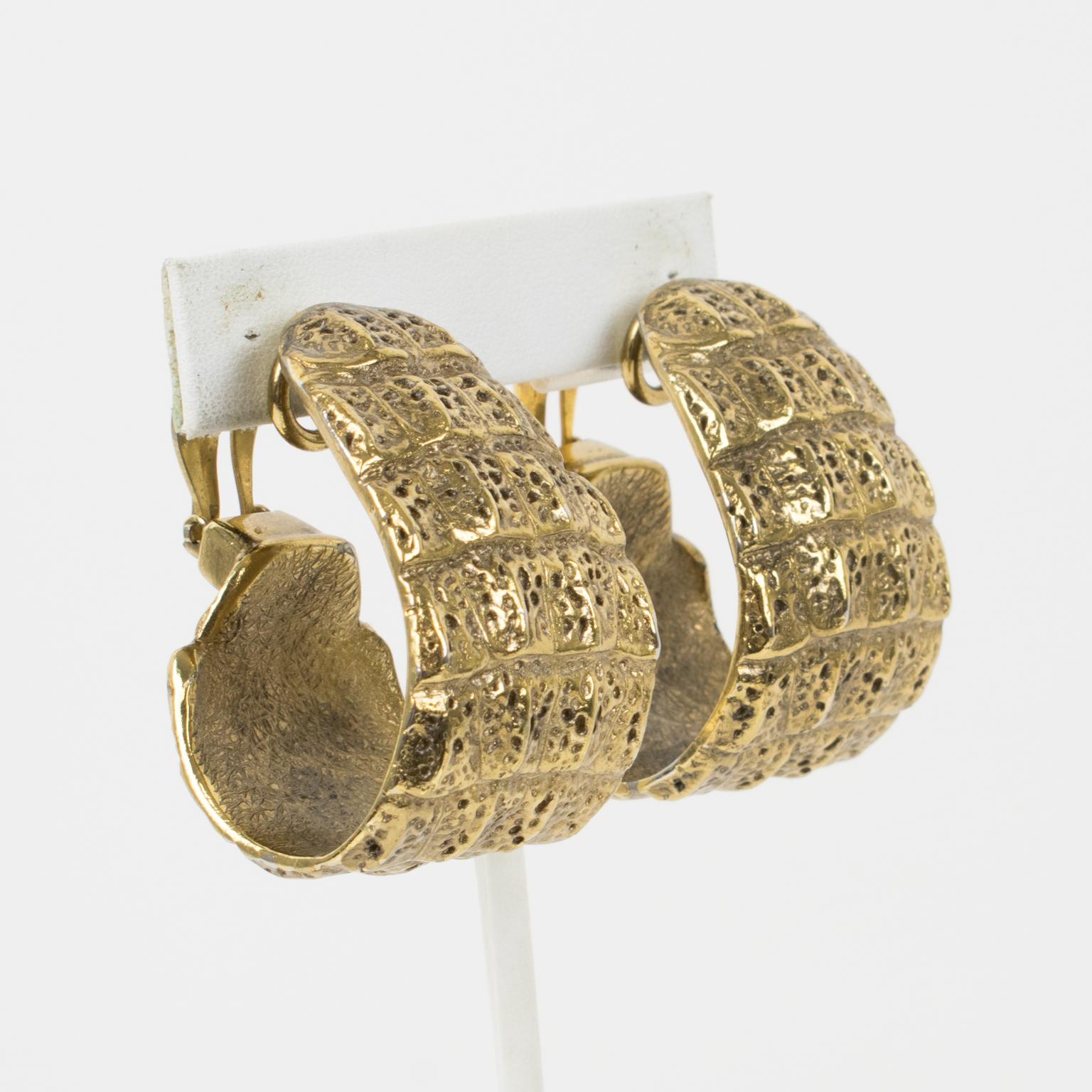These stunning Yves Saint Laurent YSL Paris hoop clip-on earrings feature a massive dimensional hoop shape with gilt metal, all textured with a crocodile embossed pattern. The earrings are signed with the 