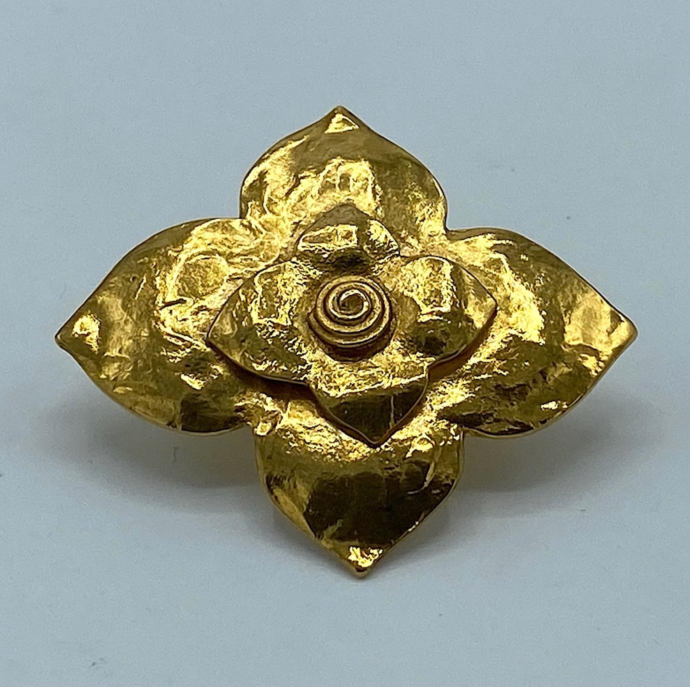 Yves Saint Laurent scarf ring in the form of a four petal flower. Martele' gold plate finish. Smaller four petal flower mounted onto the larger one. The face measures 2 inches wide, 1.75 inches high and .63 of an inch deep. The back is textured