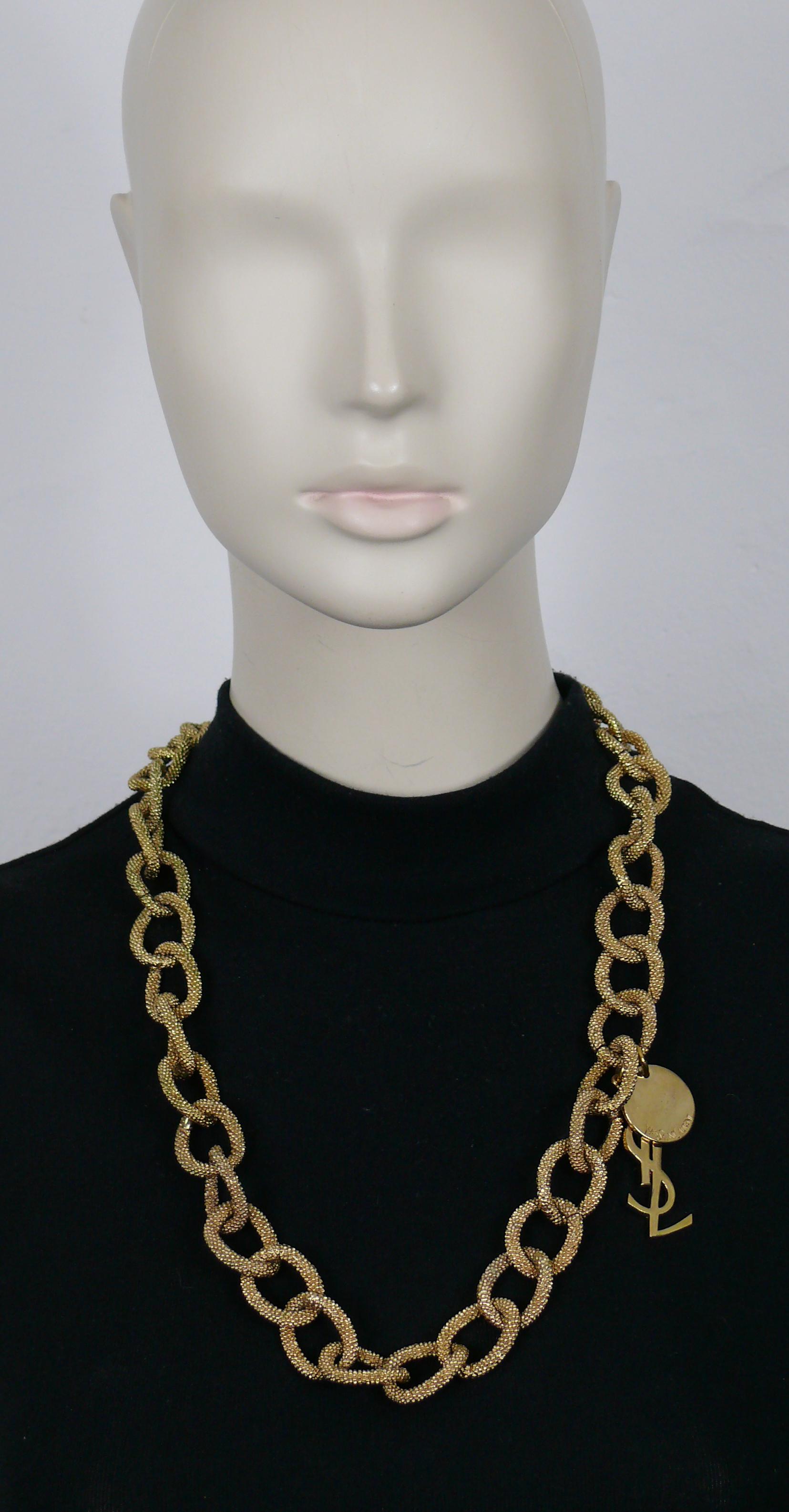 Goldfarbene YVES SAINT LAURENT-Kette mit ovalen, strukturierten Gliedern, YSL-Logo-Charme und Münz-Charme mit YVES SAINT LAURENT-Prägung.

T-Bar-Verschluss.
Einstellbare Länge.

Geprägter YVES SAINT LAURENT auf dem T-Bügel und dem