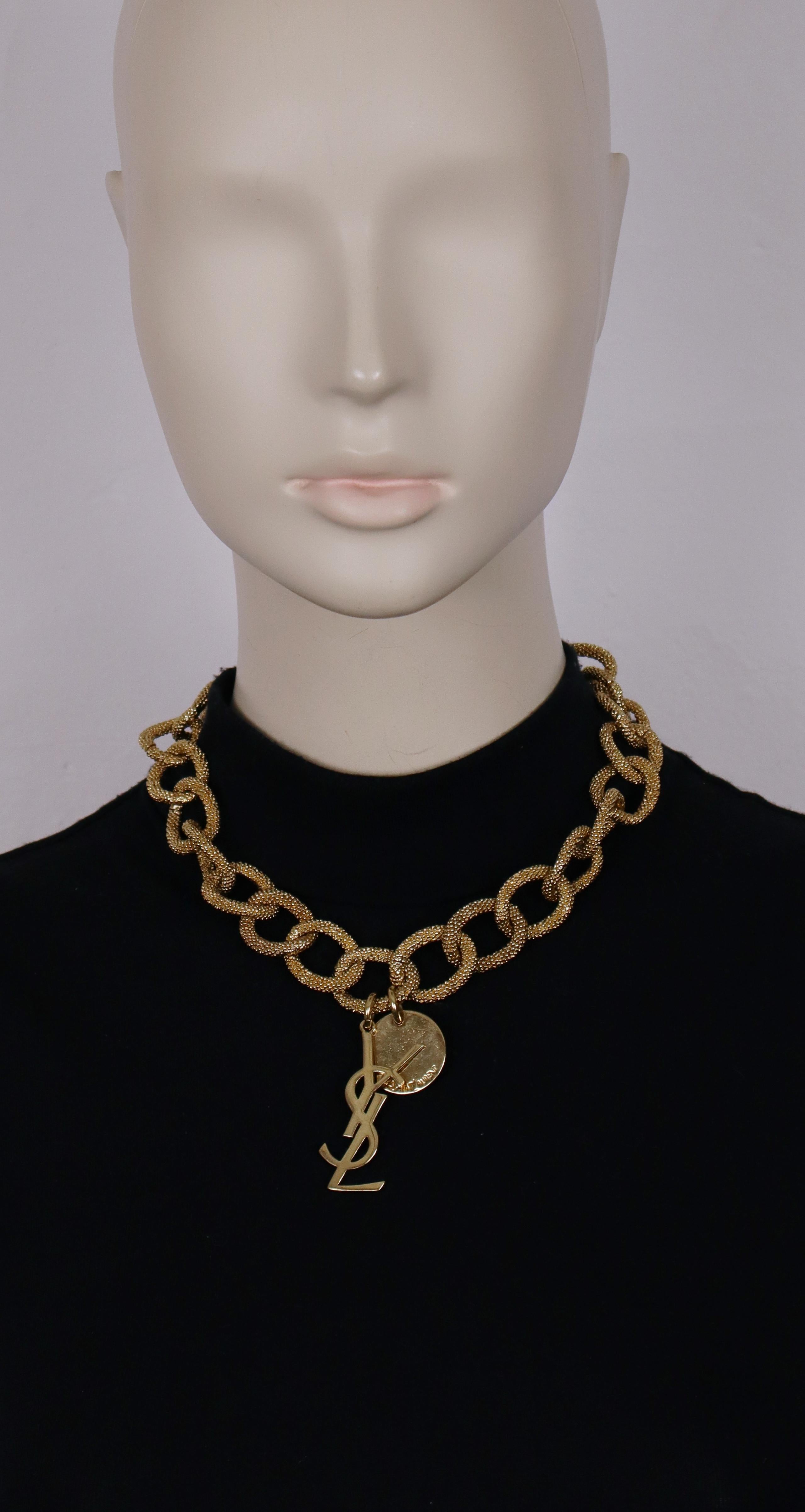 Collar de cadena dorada YVES SAINT LAURENT con eslabones ovalados texturizados, charm del logotipo YSL y charm de moneda con la inscripción YVES SAINT LAURENT.

Cierre de barra en T.
Longitud ajustable.

Grabado YVES SAINT LAURENT en la barra en T y