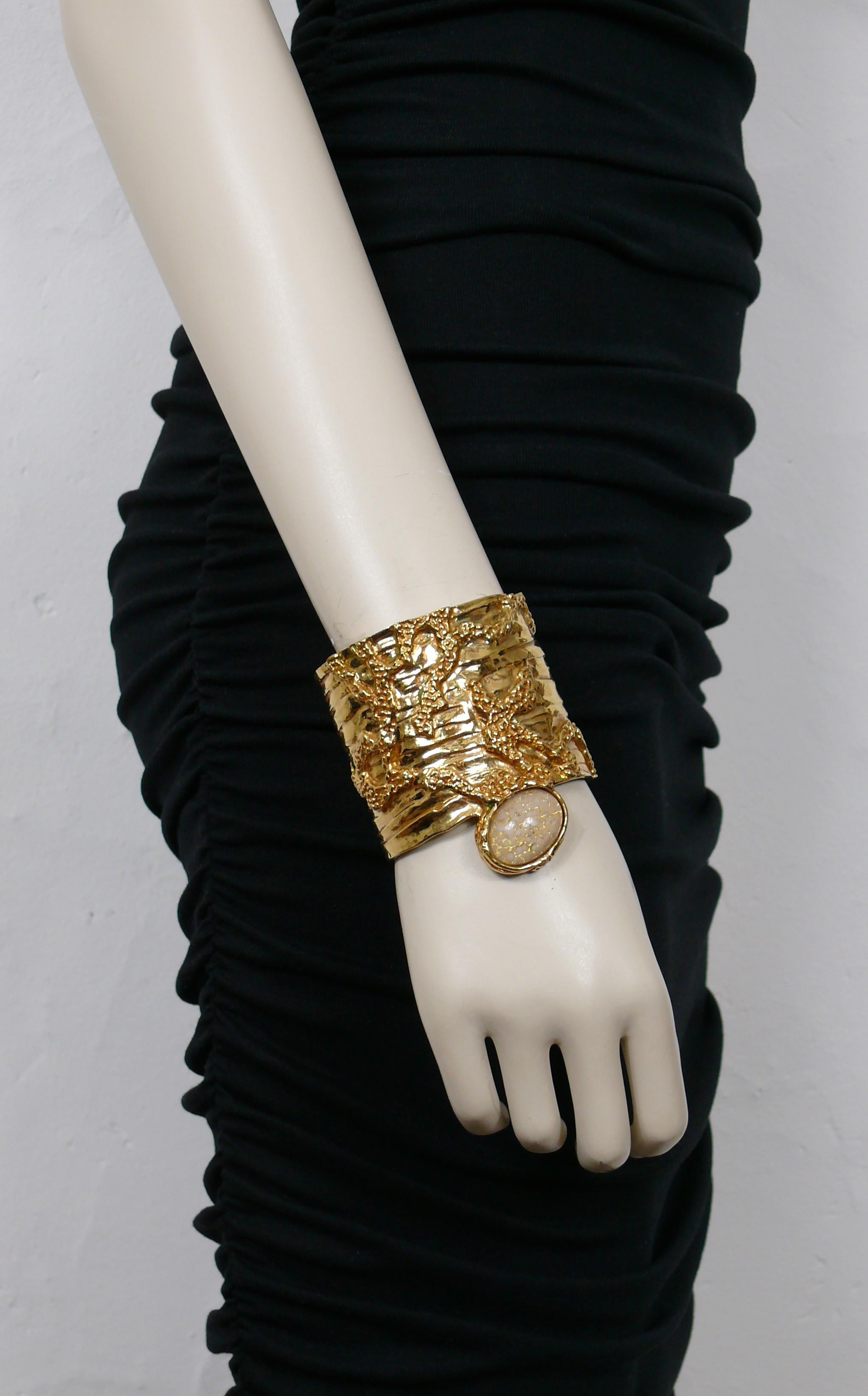 YVES SAINT LAURENT gold toned ARTY cuff bracelet featuring a textured brutalist design embellished with a gold and white glass cabochon.

Embossed with the cursive signature YVES SAINT LAURENT.

Indicated size : L.
 
Indicative measurements : inner