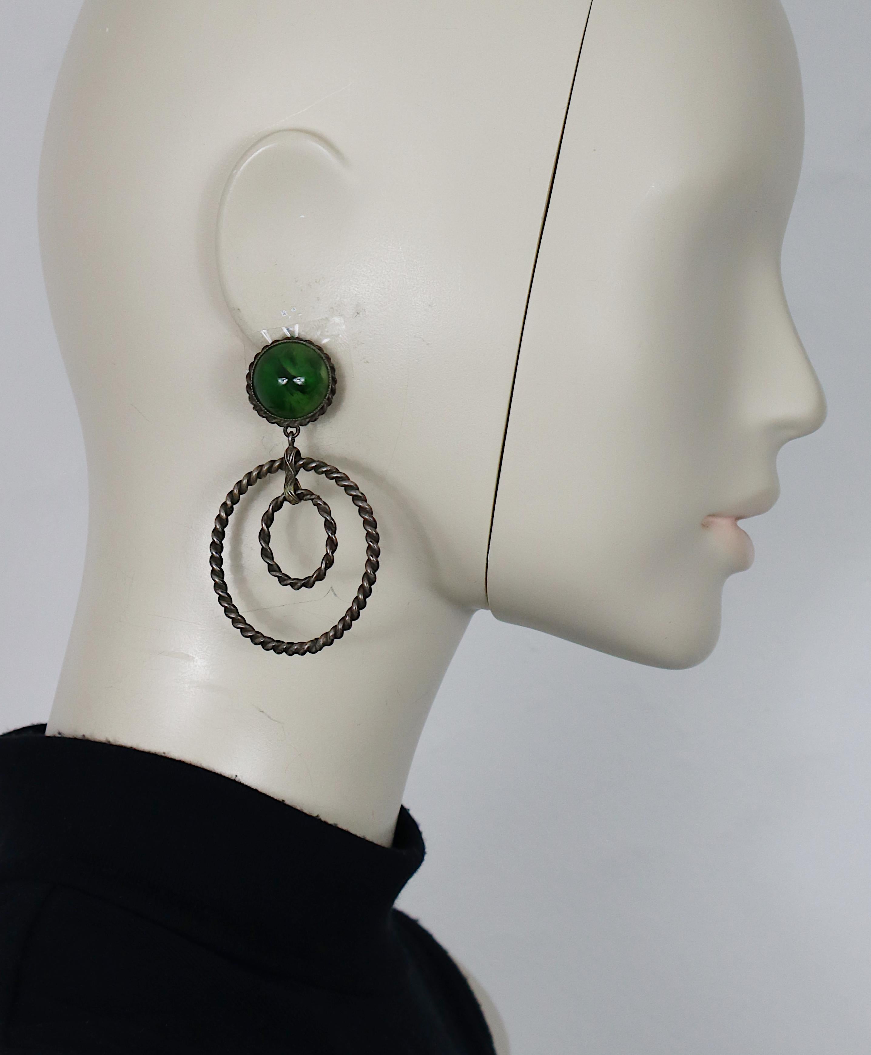 Orecchini pendenti a cerchio in filo d'argento ossidato vintage di Yves Saint Laurent (con chiusura a clip) con cabochon in resina verde marmorizzato.

Probabilmente disegnata da Roger Scemama per Yves Saint Laurent.

YSL in rilievo.

Misure