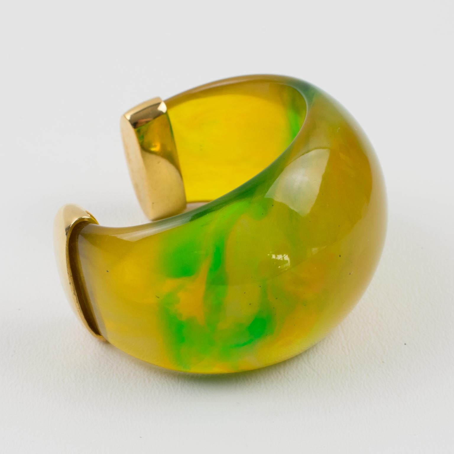 This exquisite Yves Saint Laurent YSL Paris bracelet bangle features a chunky design with a heavily domed cuff shape in translucent squash yellow marbled with green grass and tangerine orange swirling colors finished with gilt metal hardware. The