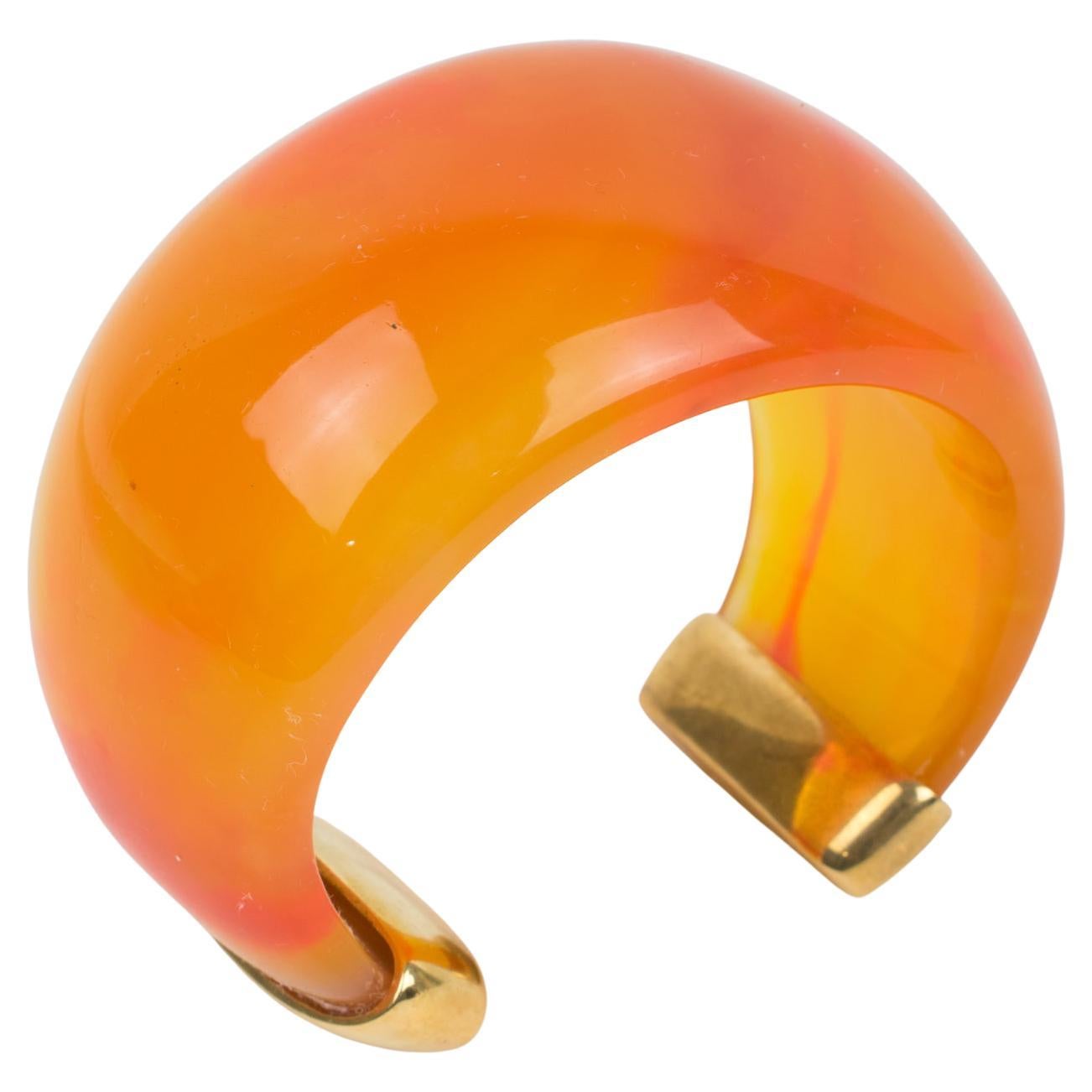 Exquisite Yves Saint Laurent YSL Paris cuff bracelet. Massive resin bracelet, featuring a heavily domed cuff in translucent bright orange with pink-red swirling colored resin finished with gilt metal hardware. Engraved marking 
