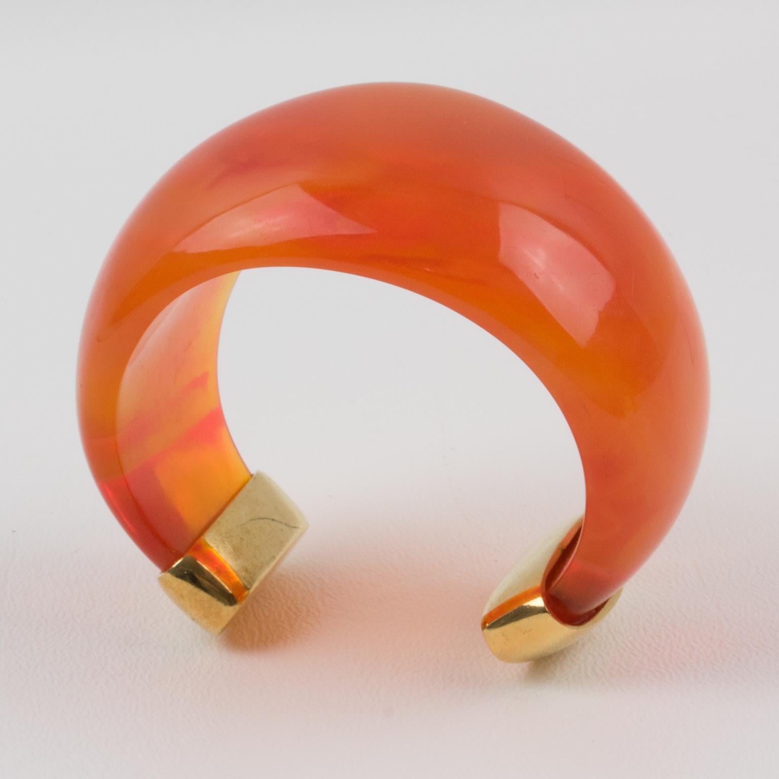 Exquisite Yves Saint Laurent YSL Paris cuff bracelet. Massive resin bracelet, featuring a heavily domed cuff in translucent bright orange marbled resin finished with gilt metal hardware. Engraved marking 