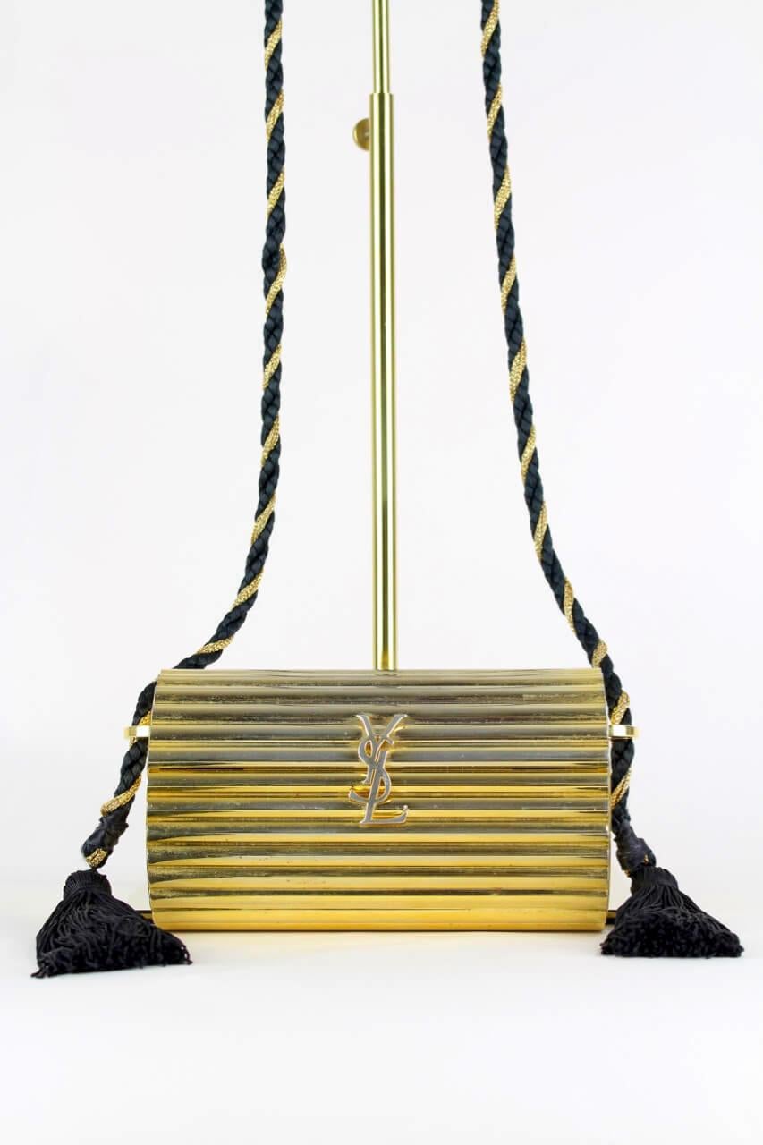 Kultige „Opium“ Yves Saint Laurent Box Bag aus goldfarbenem Metall aus den 1980er Jahren mit Schulterriemen aus Seidenkordel und Quastenverzierung. Die Tasche hat ein starres:: zylindrisches Äußeres aus einem glänzenden:: gerippten:: goldfarbenen