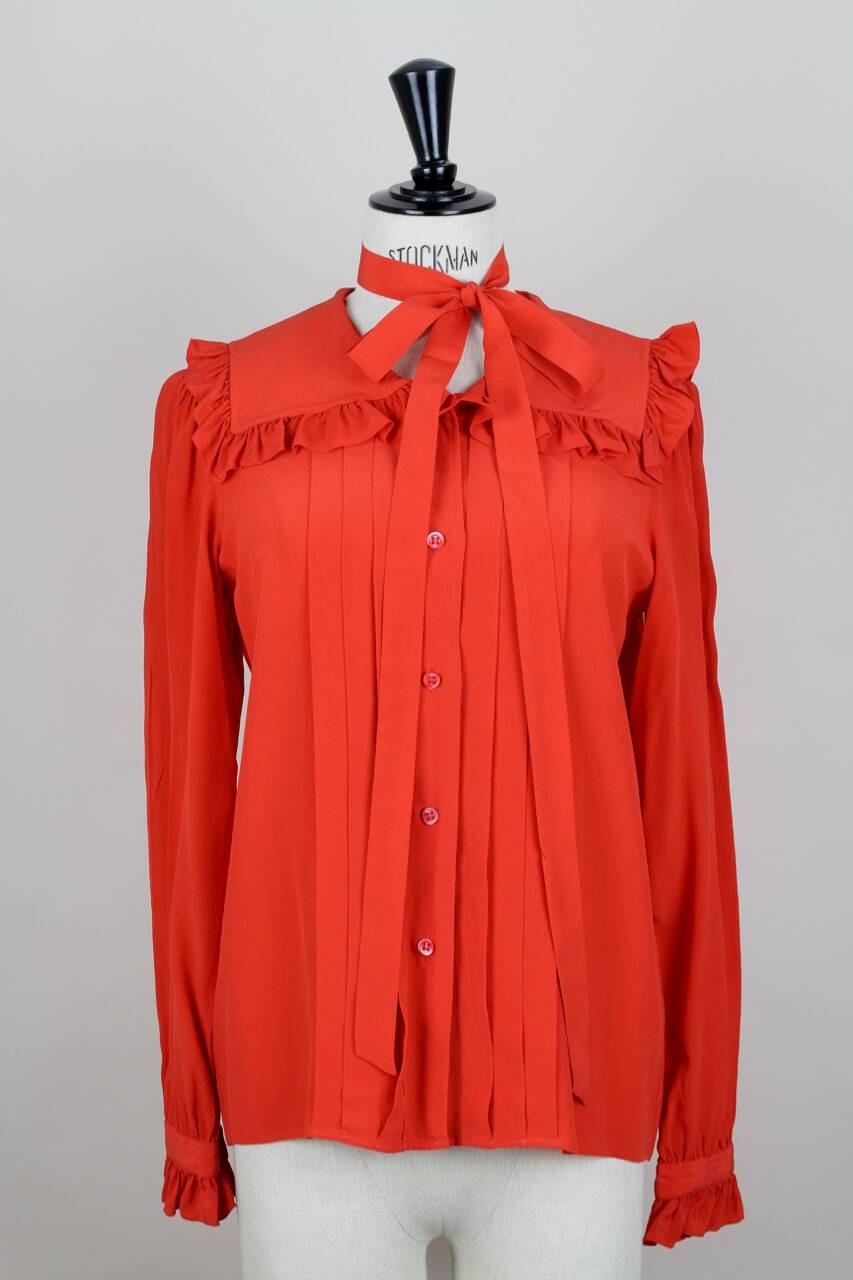 This beautiful unusual design vintage Yves Saint Laurent 1970's blouse is made from tangerine silk and has a ruffled sailor collar and a tuxedo style detail through the panels of fabric that run down the front. The long sleeves feature the YSL