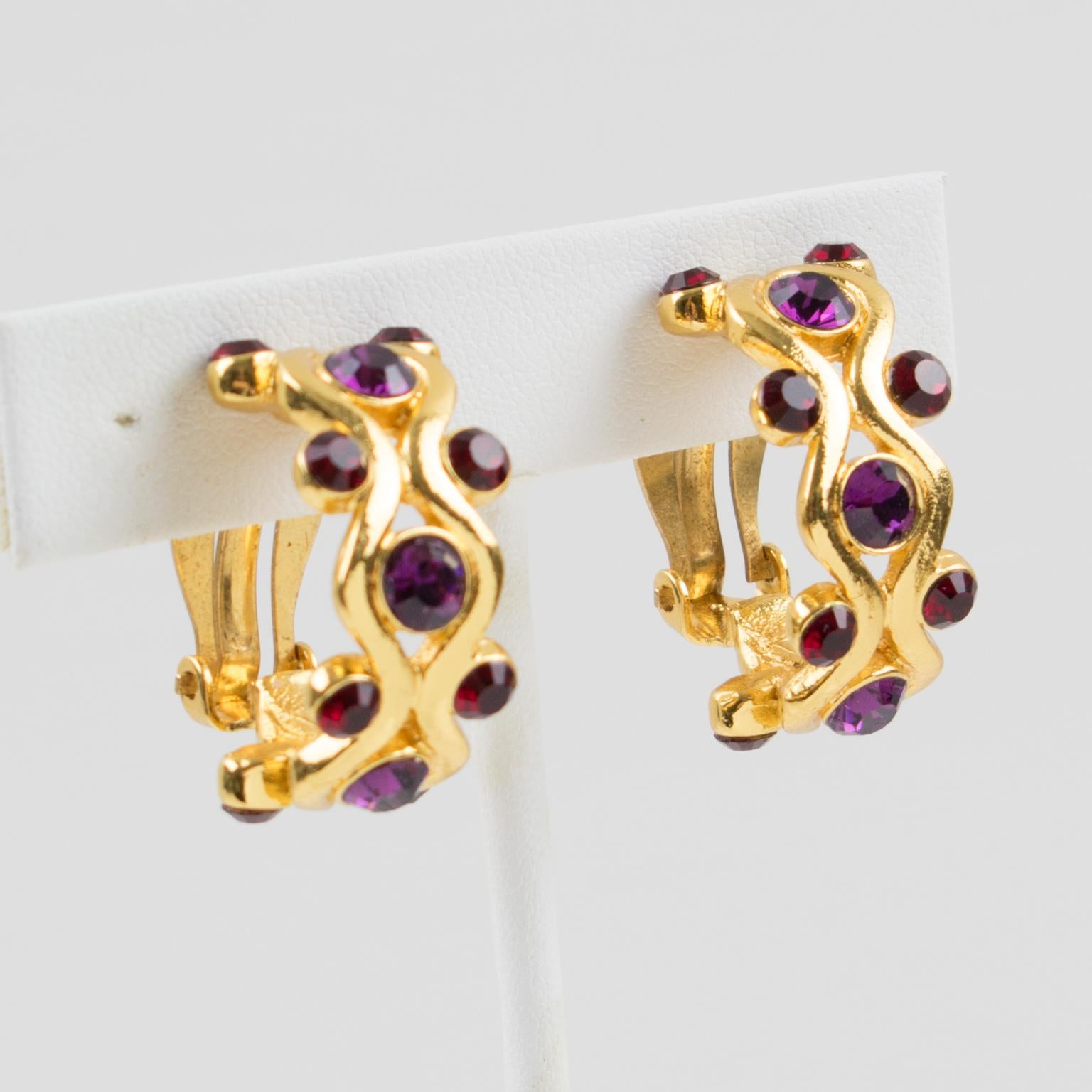 Stylish Yves Saint Laurent YSL Paris signed clip-on earrings. Featuring a dimensional half hoop shape with shiny gilt metal all carved, ornate with purple and ruby red crystal rhinestones. Signed with 