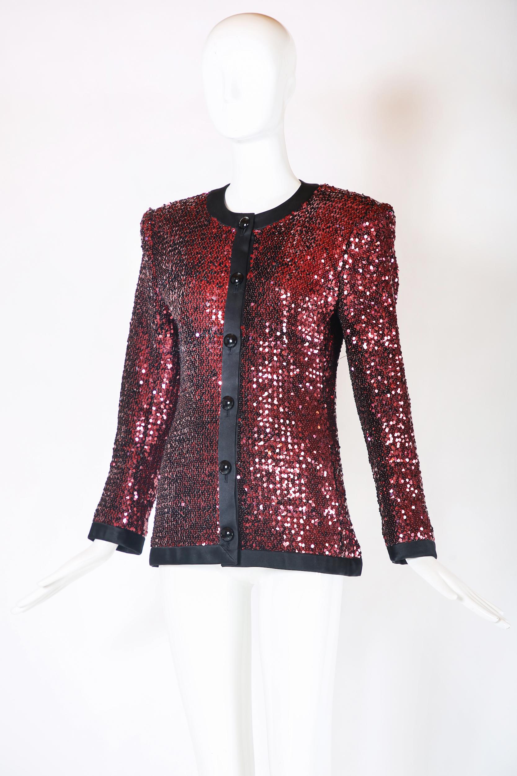 Vintage Yves Saint Laurent dinner jacket covered with reddish/dark pink sequins and trimmed with black silk. Features oversized black dome-shaped buttons and is lined in silk at the interior. Tag size 38 but please consult measurements as vintage