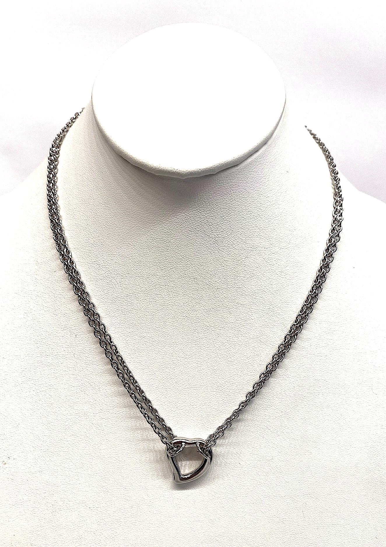 A double strand sterling silver heart pendant necklace by Yves Saint Laurent. Each side of the necklace is a sterling cable link strand that start at the clasp, descends down to the hear, loops through it and back up to the clasp 7.5 inches long. An