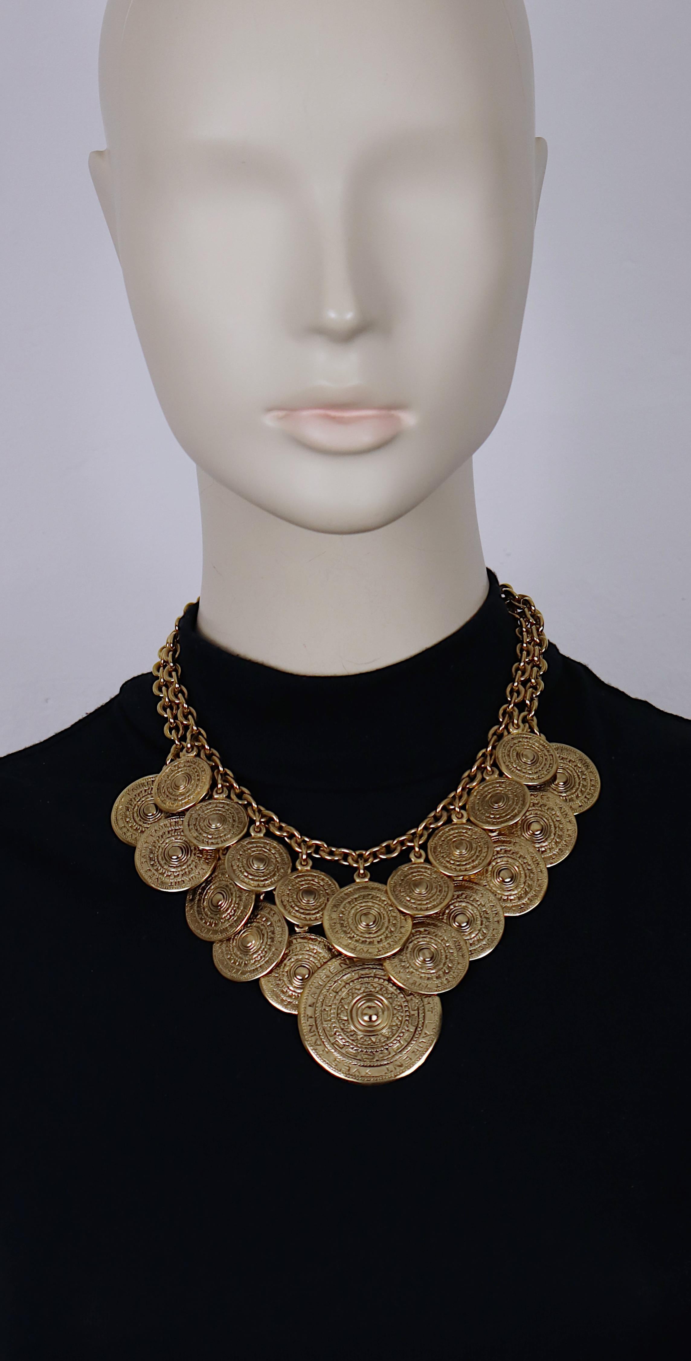 Collana vintage di Charme Antiques in oro anticato a due livelli con dischi etnici a motivo azteco con l'incisione Yves Saint Laurent.

Chiusura a molla con aragosta.

YSL in rilievo.
Etichetta metallica pendente YSL.

Misure indicative: lunghezza