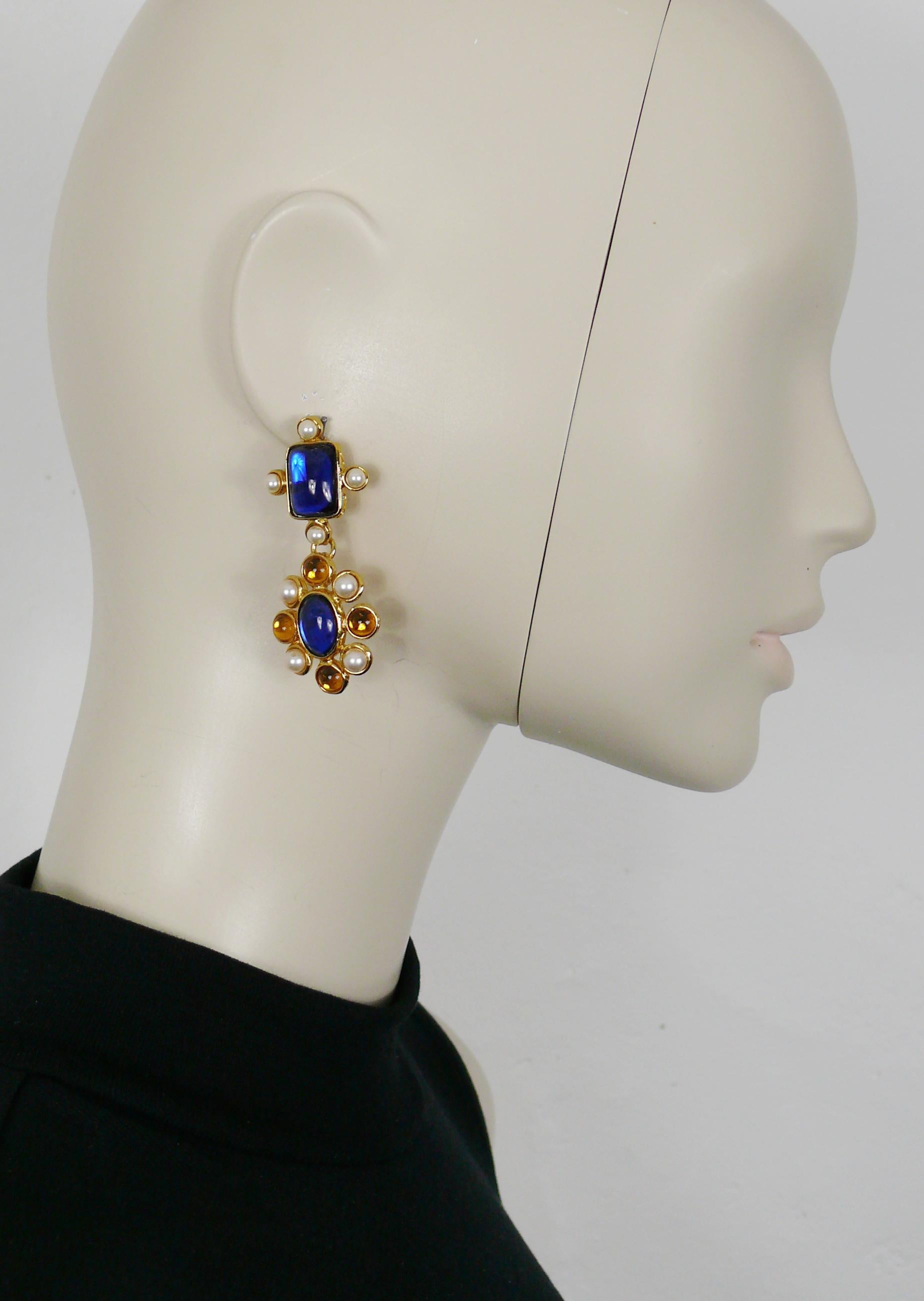 YVES SAINT LAURENT vintage gold toned dangling earrings (clip-on) featuring a stylized flower pendant embellished with a blue oval resin cabochon, faux pearls and orange glass cabochons, topped by a blue resin cabochon cross adorned by faux