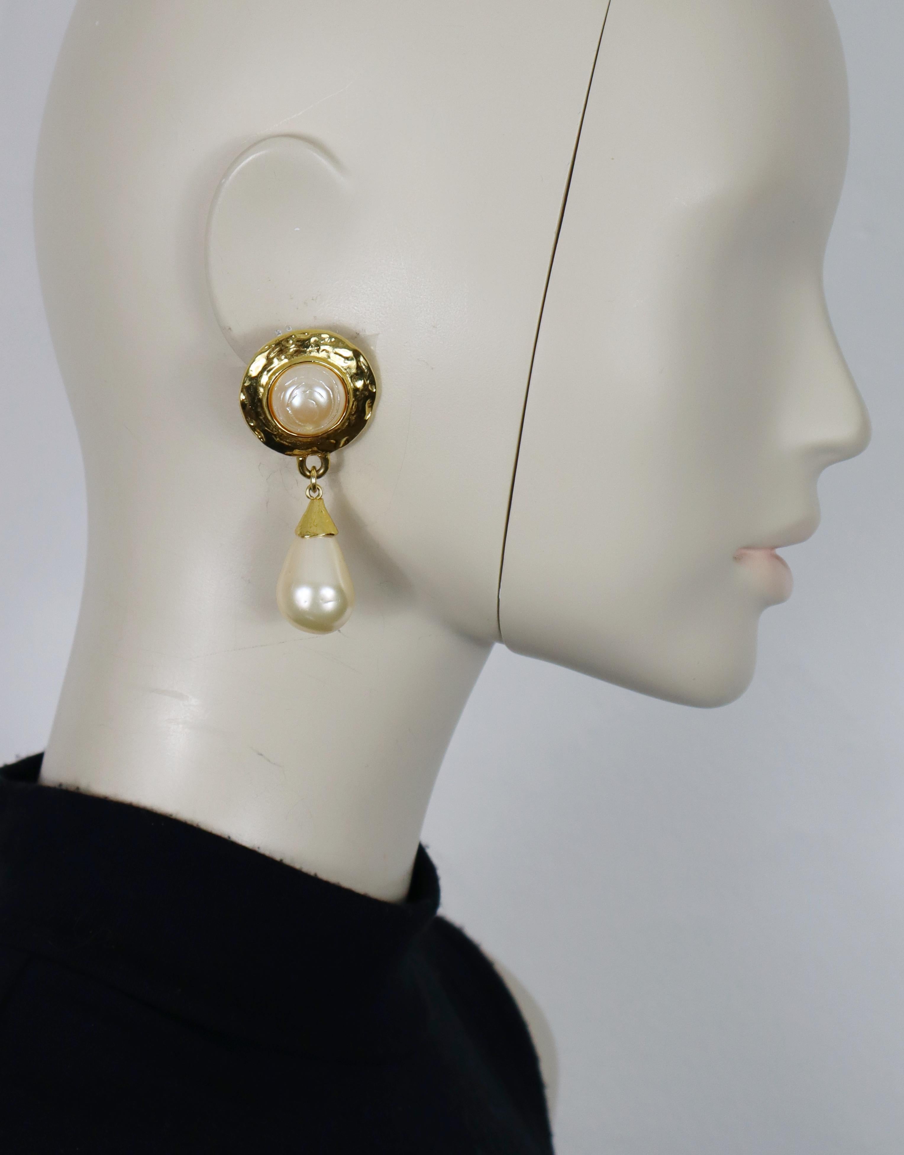 Orecchini pendenti Yves Saint Laurent vintage in tonalità oro (con chiusura a clip) impreziositi da perle finte.

YSL in rilievo.

Misure indicative: altezza massima circa 6,5 cm (2,56 pollici) / larghezza massima circa 3 cm (1,18 pollici).

Peso