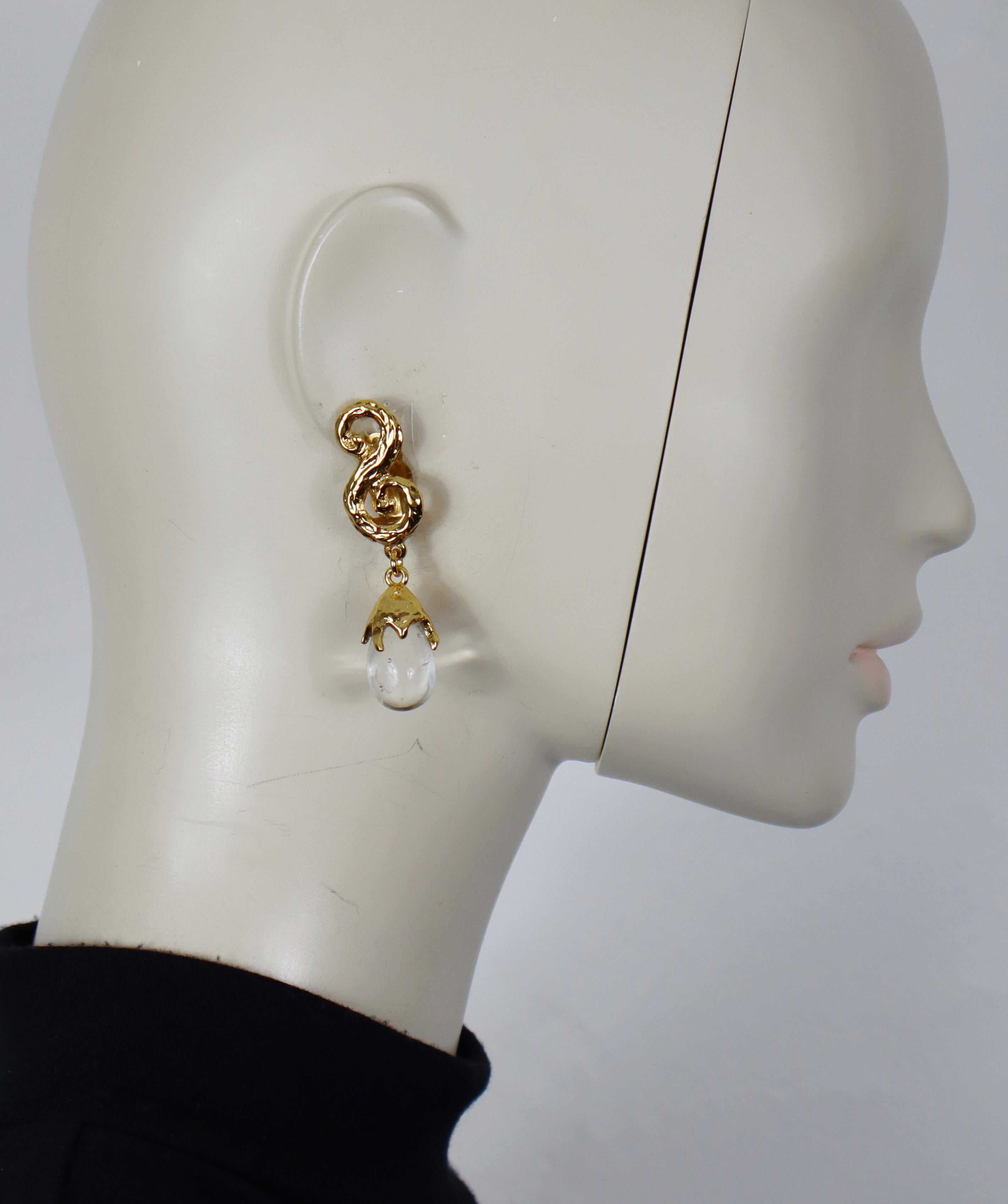 Pendientes colgantes vintage YVES SAINT LAURENT de pergamino en tono dorado texturizado (con clip) con gota de cristal transparente jaspeado.

Estampado YSL Made in France.

Medidas orientativas: altura aprox. 6 cm / anchura máx. aprox. 1,5