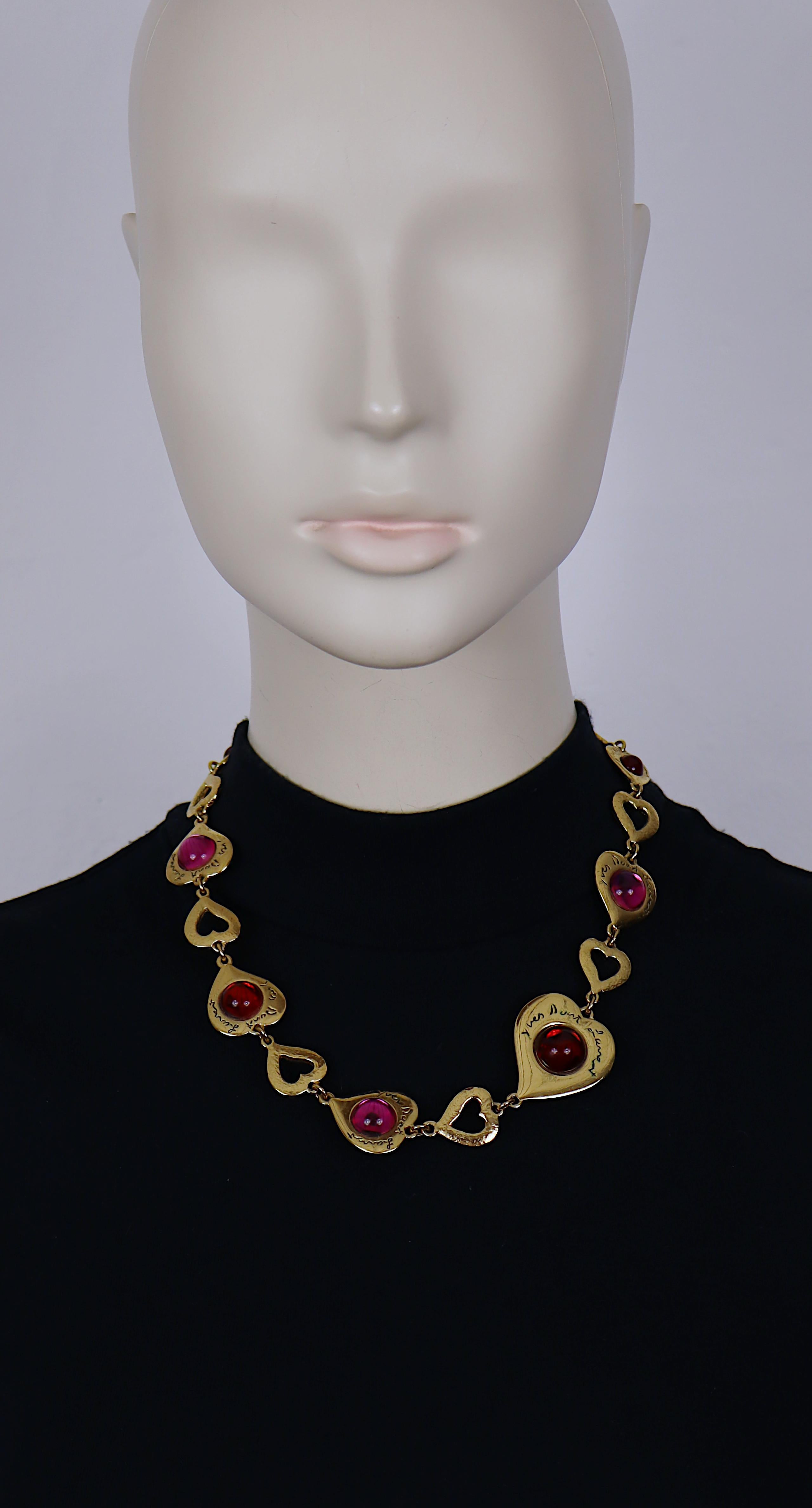 Yves Saint Laurent, collana vintage a maglie con cuore in tonalità oro impreziosita da cabochon in vetro rosso e fucsia.

Chiusura a cuore regolabile con alamari.

La firma in corsivo di Yves Saint Laurent è impressa sugli alamari a cuore.

Misure