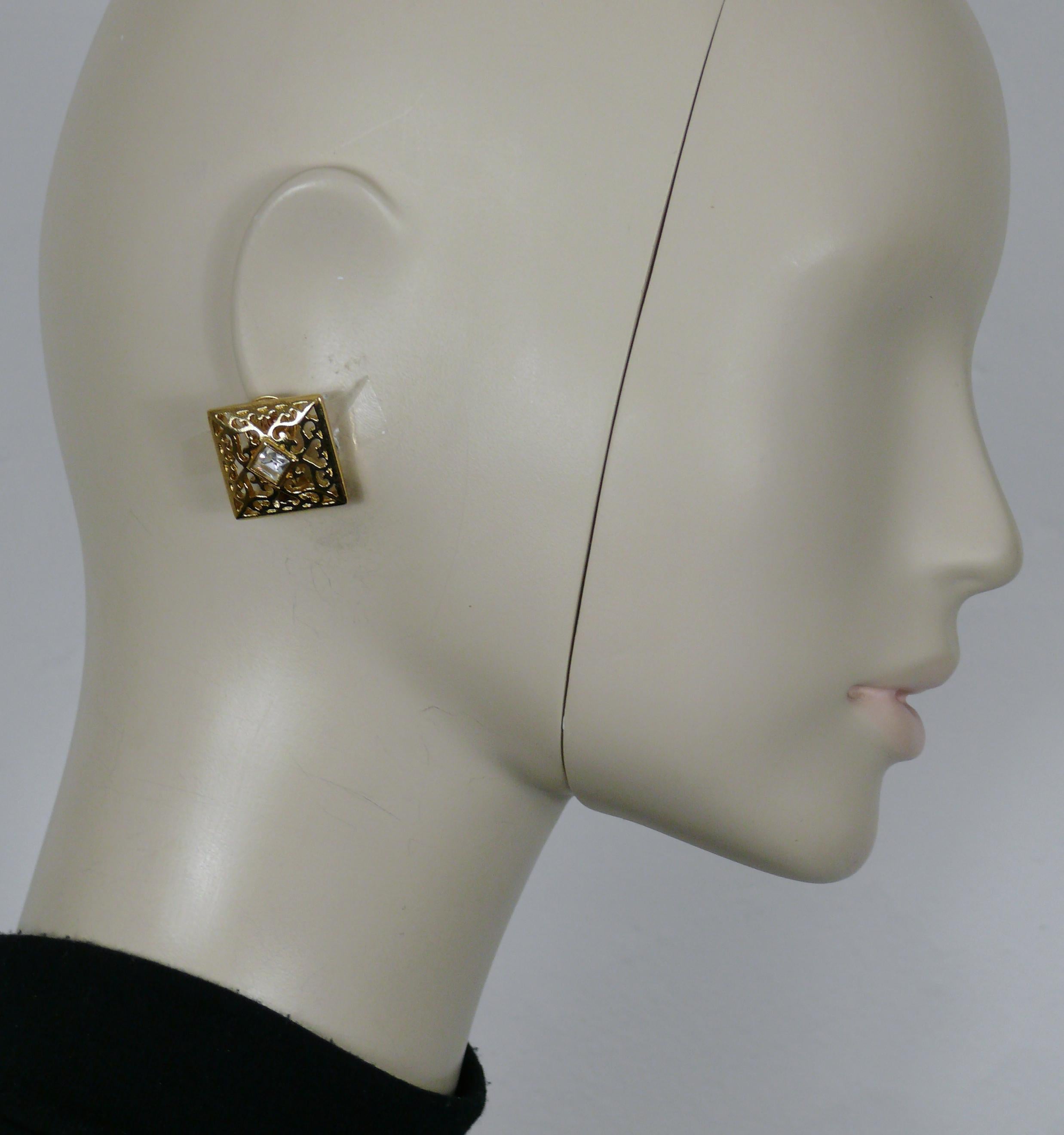 YVES SAINT LAURENT durchbrochene Ohrringe in Goldton, die in der Mitte mit einem klaren Kristall verziert sind.

Geprägtes YSL.

Ungefähre Maße: Höhe ca. 2,3 cm (0,91 inch) / Breite ca. 2,4 cm (0,94 inch).

Gewicht pro Ohrring: ca. 5