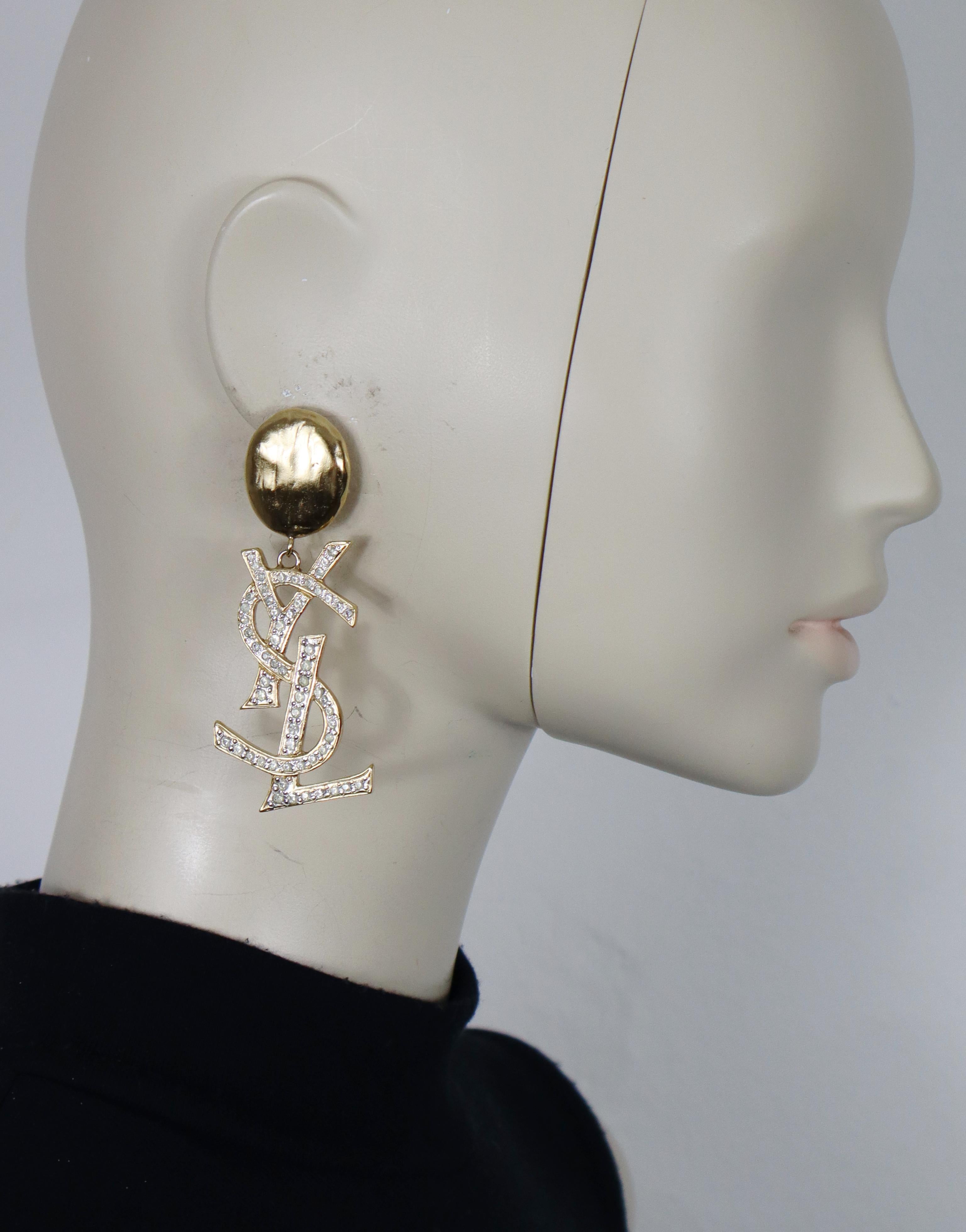 YVES SAINT LAURENT Vintage-Ohrringe in massivem Goldton mit dem YSL-Monogramm, das mit klaren Kristallen verziert ist (Clip-on).

Geprägtes YSL.

Ungefähre Maße: Höhe ca. 8 cm (3,15 Zoll) / max. Breite ca. 2,6 cm (1,02 Zoll).

Gewicht pro Ohrring: