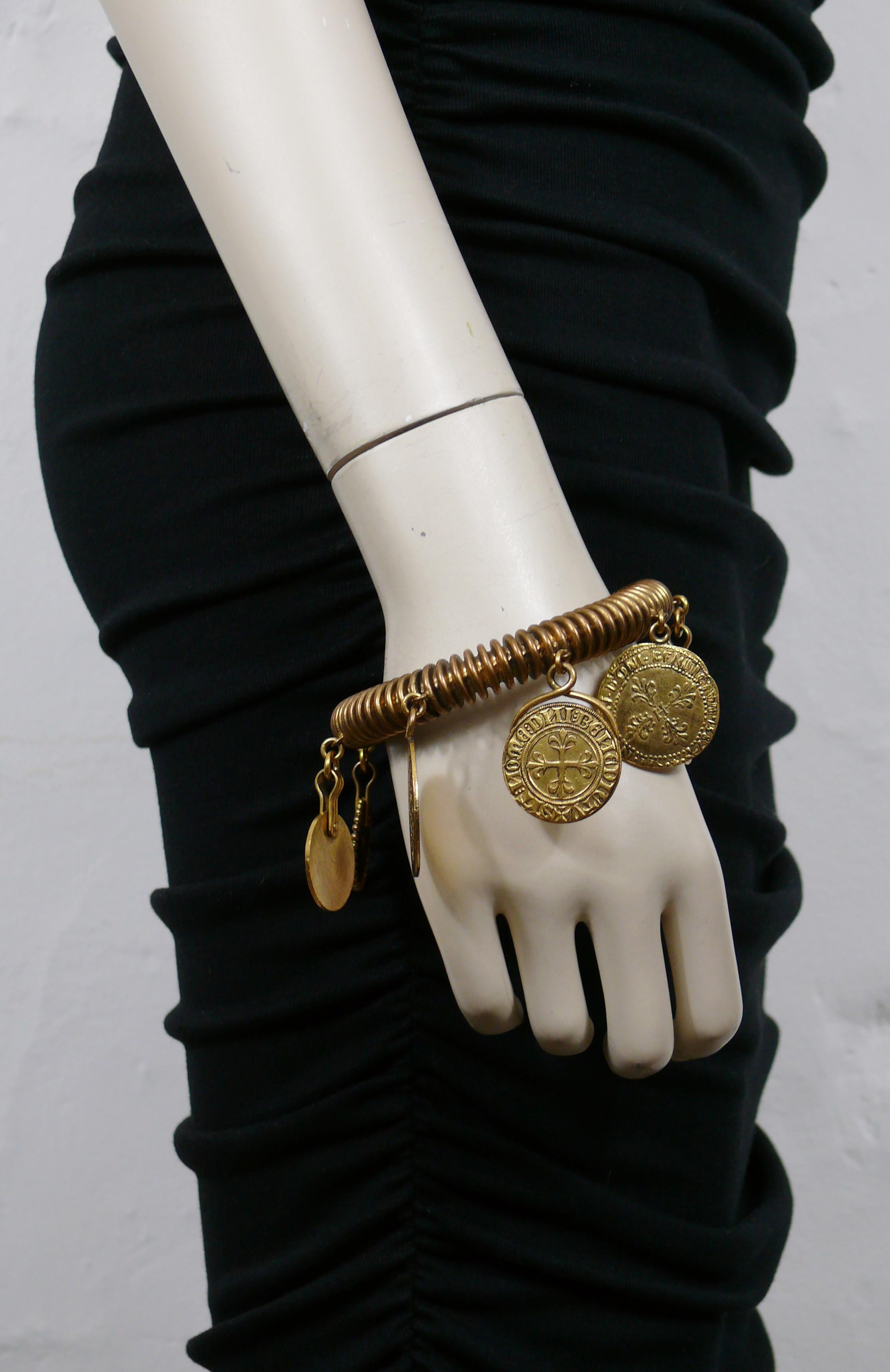 YVES SAINT LAURENT vintage bracelet rigide en fil de fer, ton bronze antique, orné de divers charms en forme de médailles.

S'enfile (pas de fermeture).

YSL en relief sur le revers d'une médaille.

Mesures indicatives : circonférence intérieure